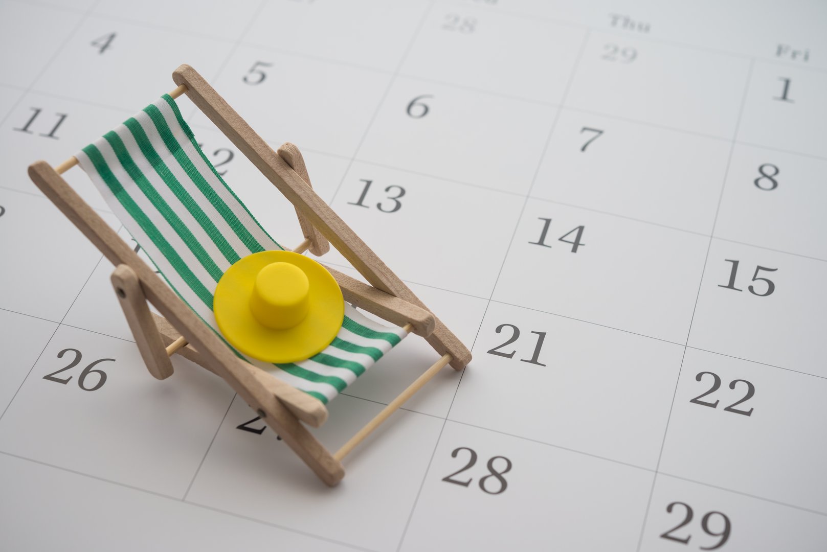 Green beach chair and hat on white blank calendar background copy space. Annual leave travel period for relaxation concept. Period of paid time off (PTO) granted to employees by their employer.