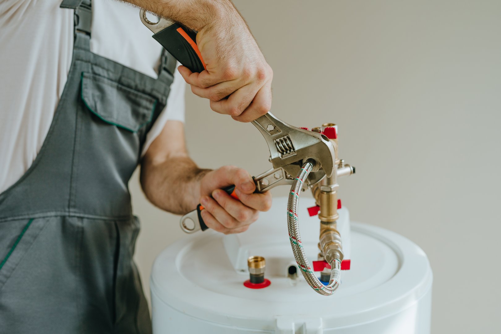 Man fixing water heater. Close-up view of male hands using wrench.