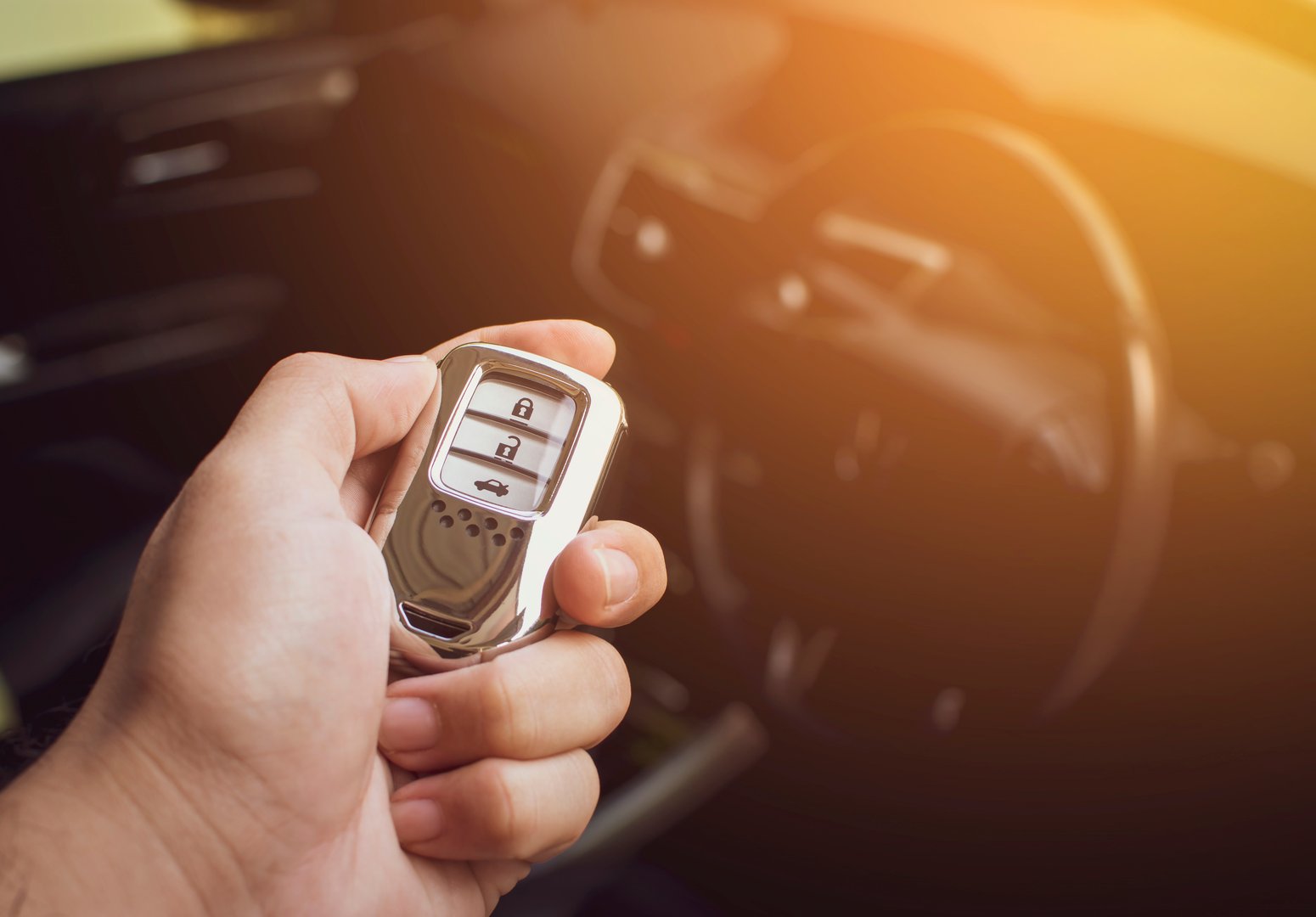 Driver's hand holding the car keyless remote.