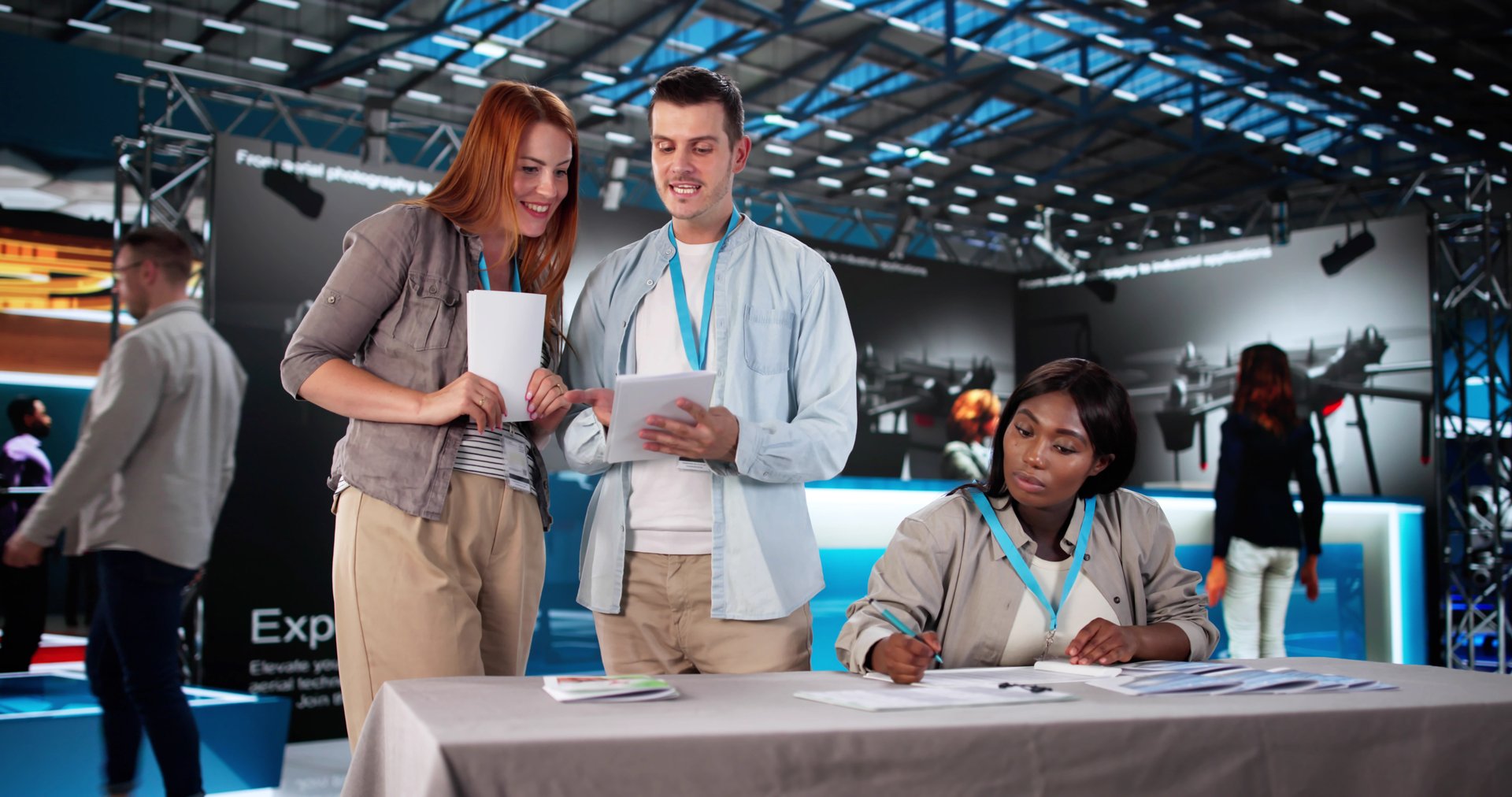 The Executive Giving A Presentation At A Busy Trade Show.