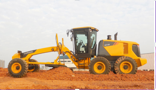 A yellow road grader on a construction site with red soil, under a cloudy sky, smoothing the ground surface.