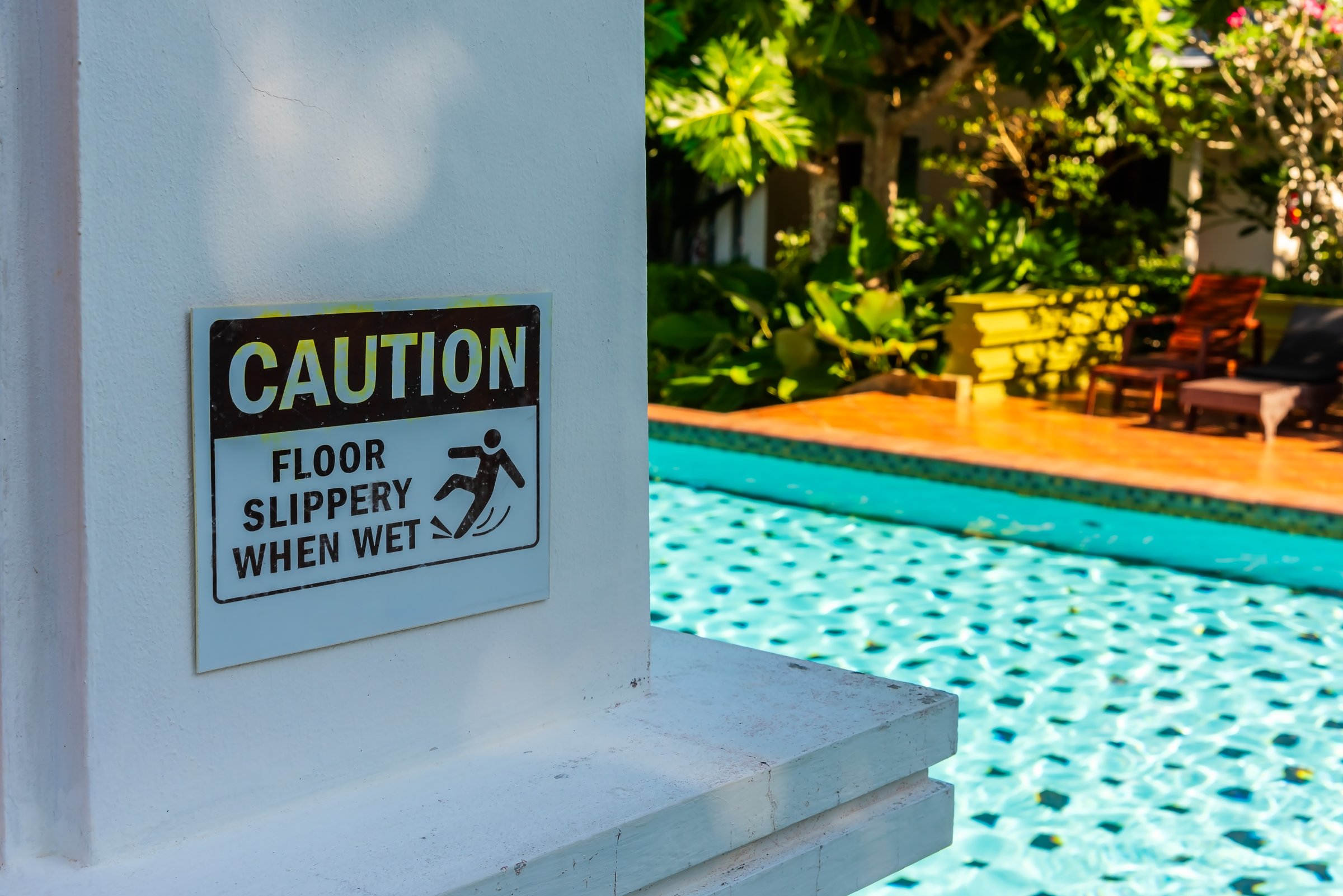 Floor slippery when wet caution sign at swimming pool.