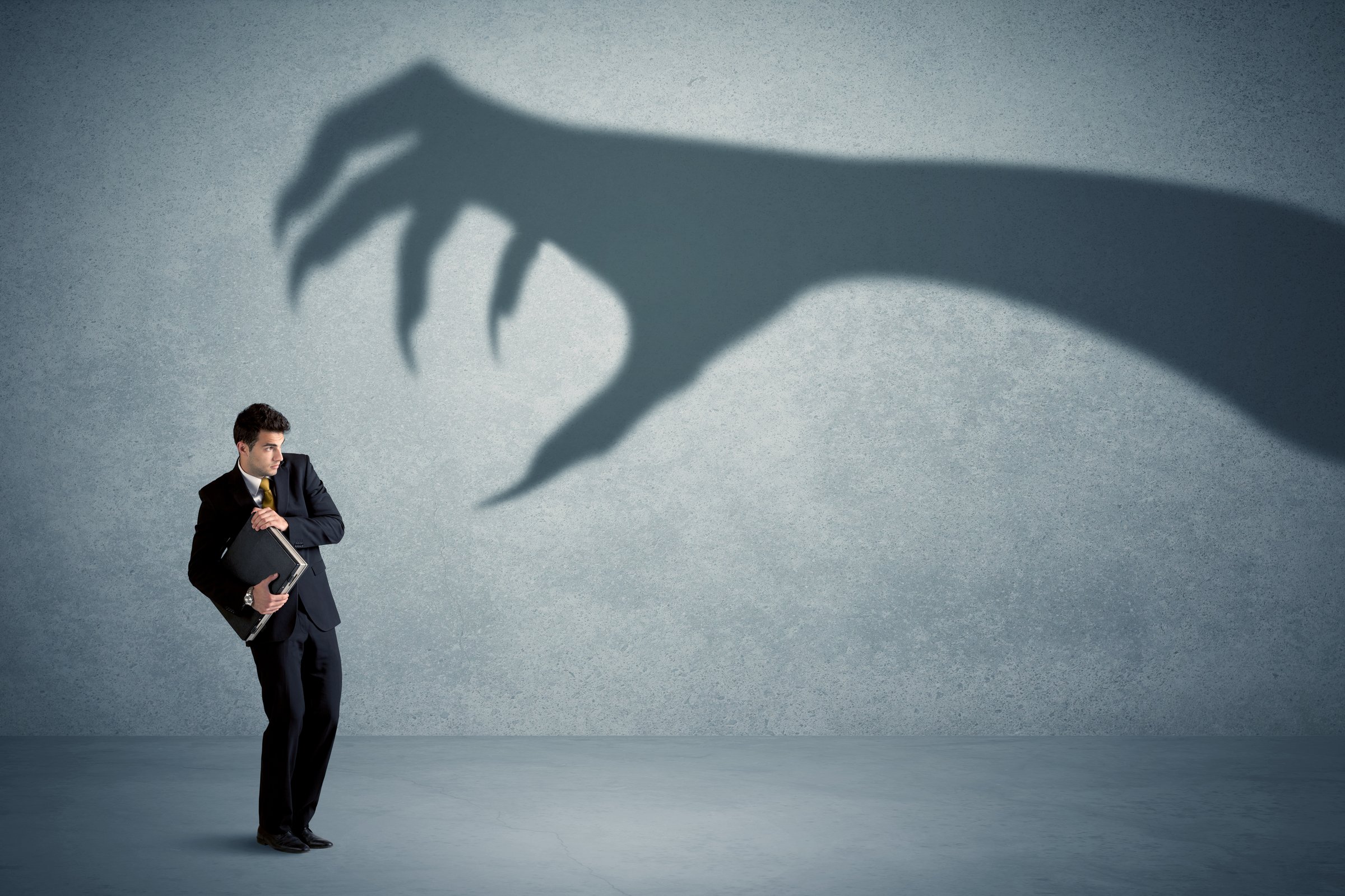 Business person afraid of a big monster claw shadow concept on background