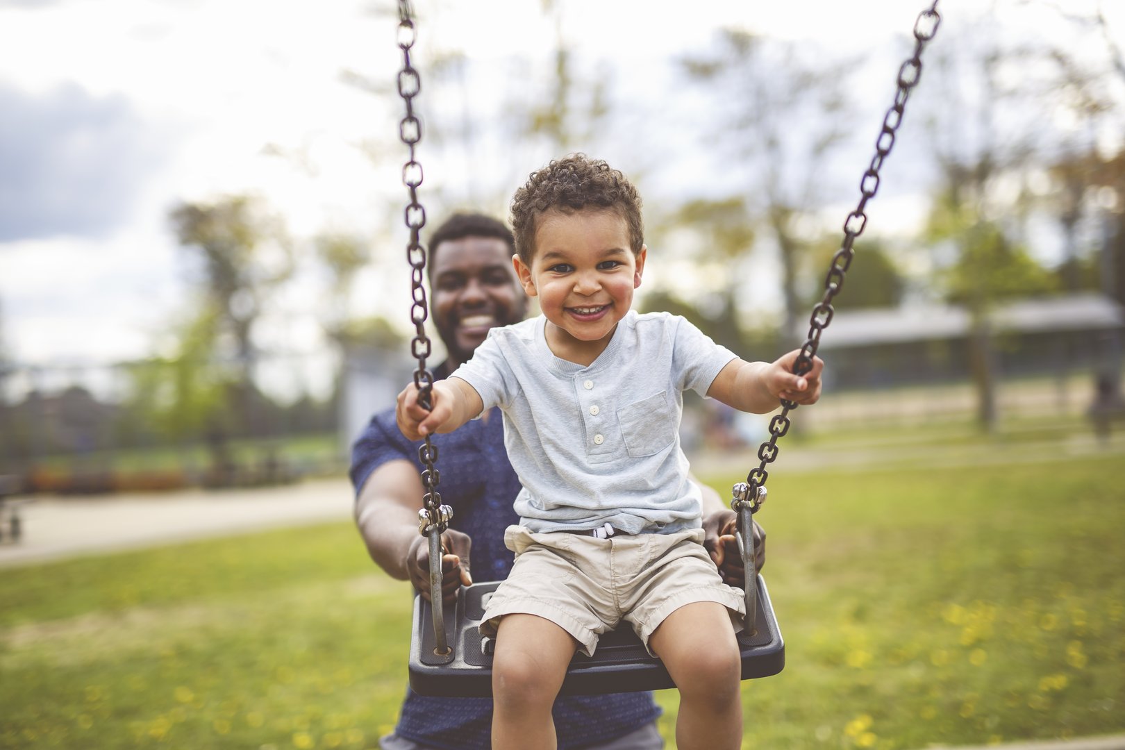 A Playtime Moments. father With Her son Swinging Having Fun on the Playground Outside, Sharing Laughter and Joyful Bonding In Park Outdoors