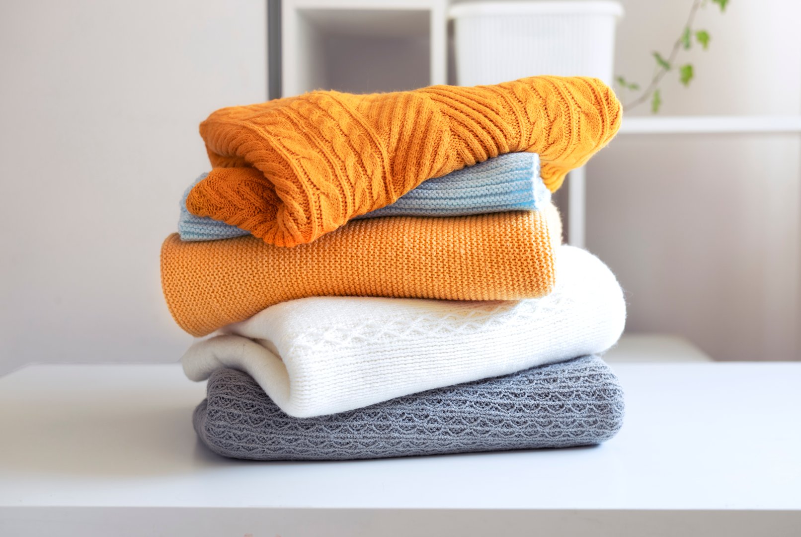 Stack of knitted folded clothes on table.Knittings pile.Autumn clothing heap.Woolen sweaters.Objects.Nobody.