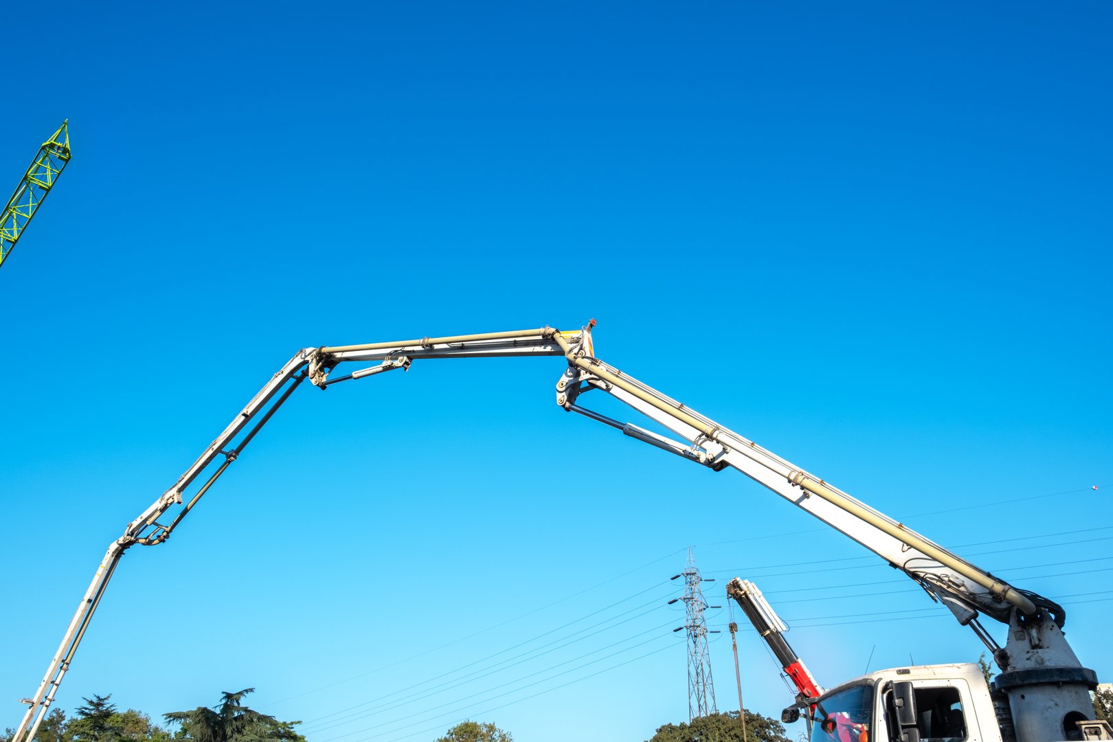 Concrete pump truck. High voltage lamppost and blue sky in the background