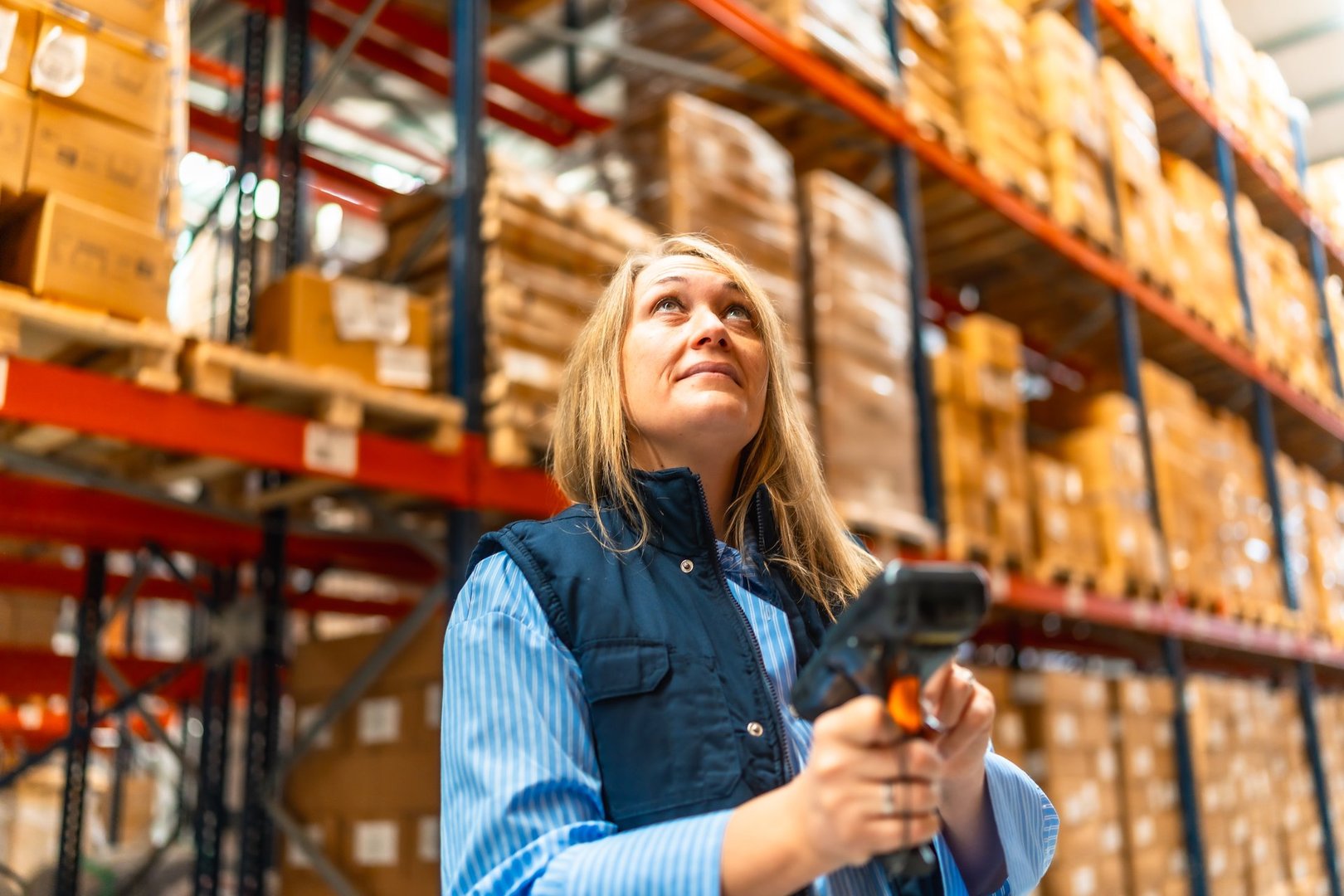 Woman worker scanning package with bar code reader in a distribution warehouse