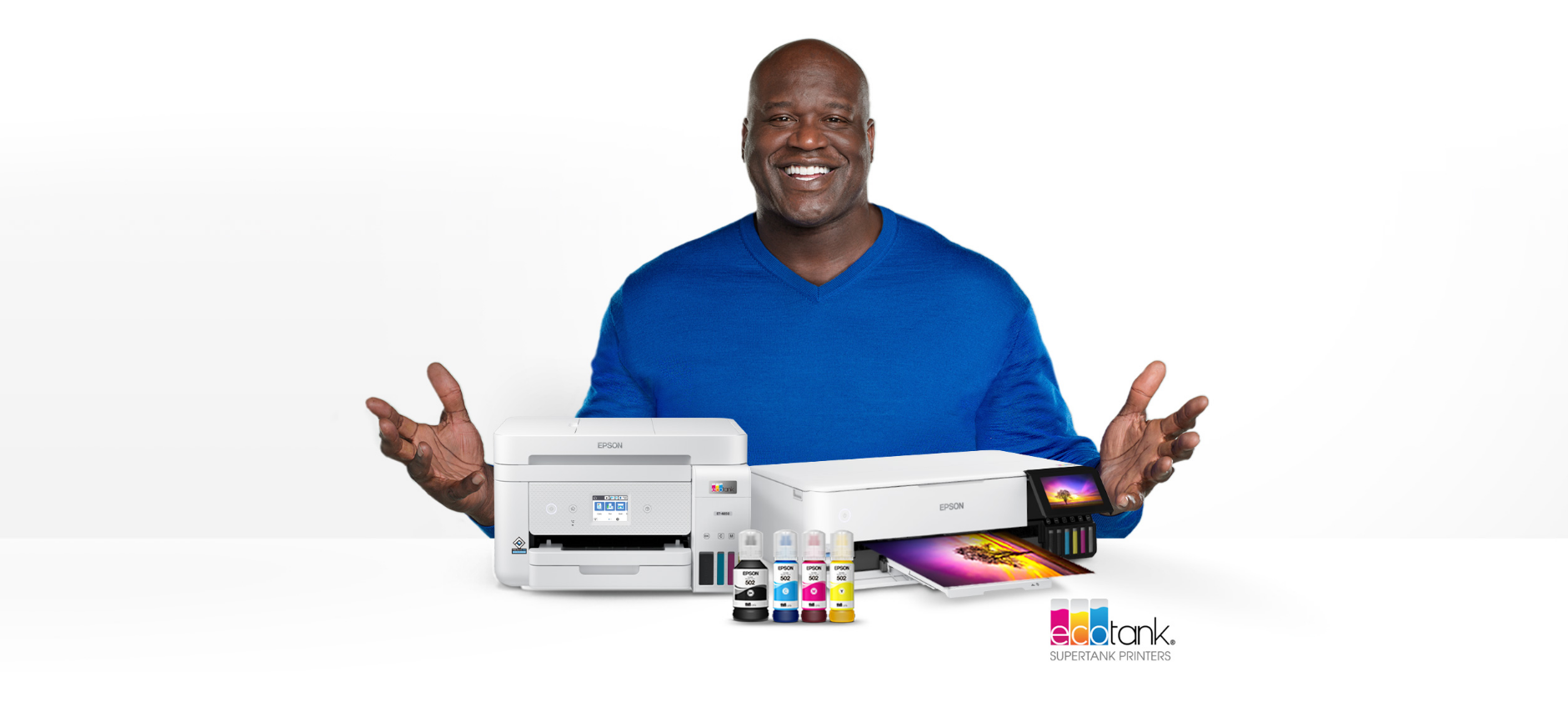 A smiling man in a blue shirt poses with Epson printers and ink bottles on a white background.