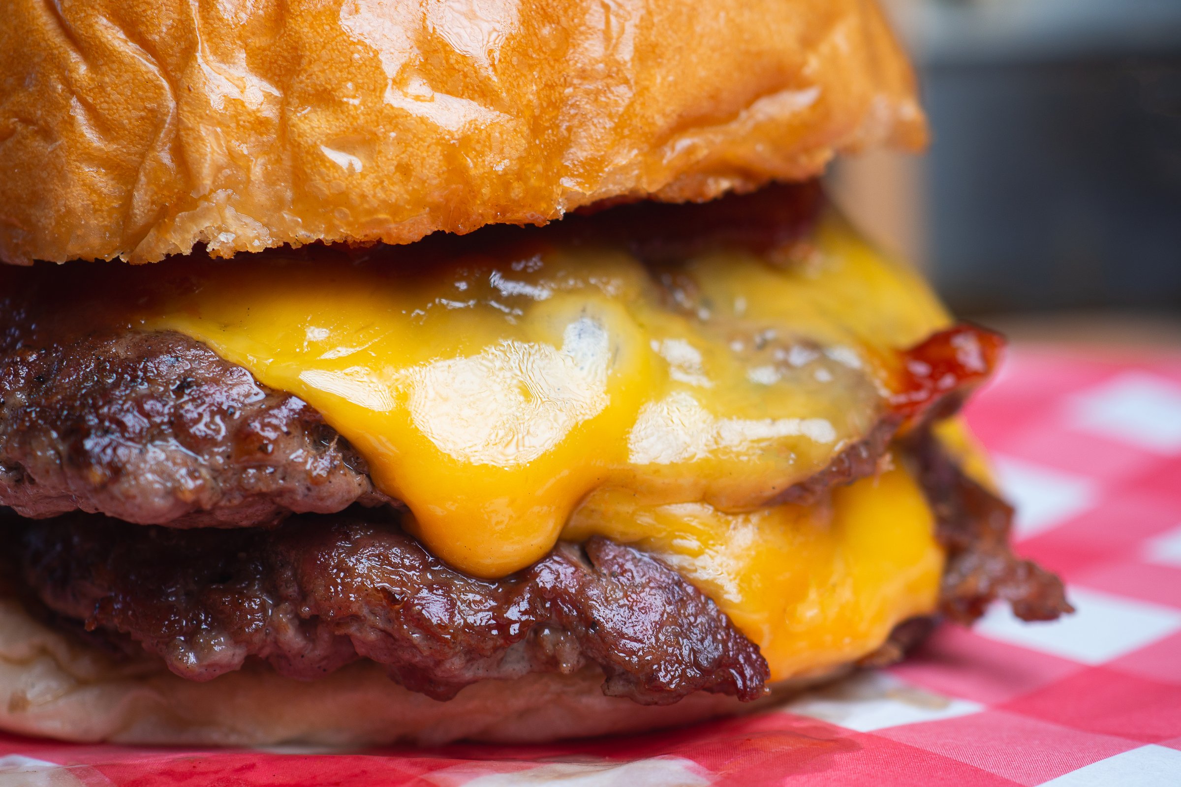 Juicy hamburger layered with two grilled beef patties and cheddar cheese, oozing under a shiny bun, ideal for showcasing comfort food, BBQ, or gourmet fast food imagery.