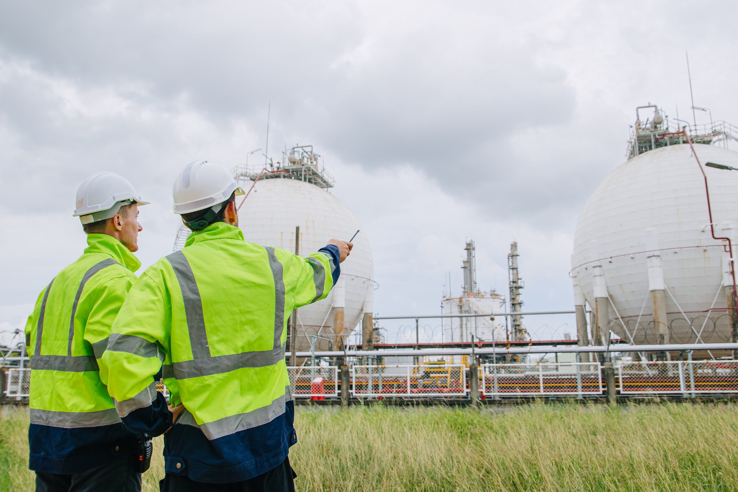 Industrial engineers workers in a refinery oil and gas LNG tank, Engineers collaborate with friend together at the oil storage tanks site.