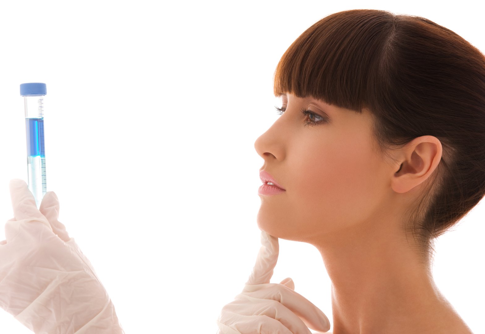 Woman wearing gloves examines a test tube with blue liquid, set against a plain white background.
