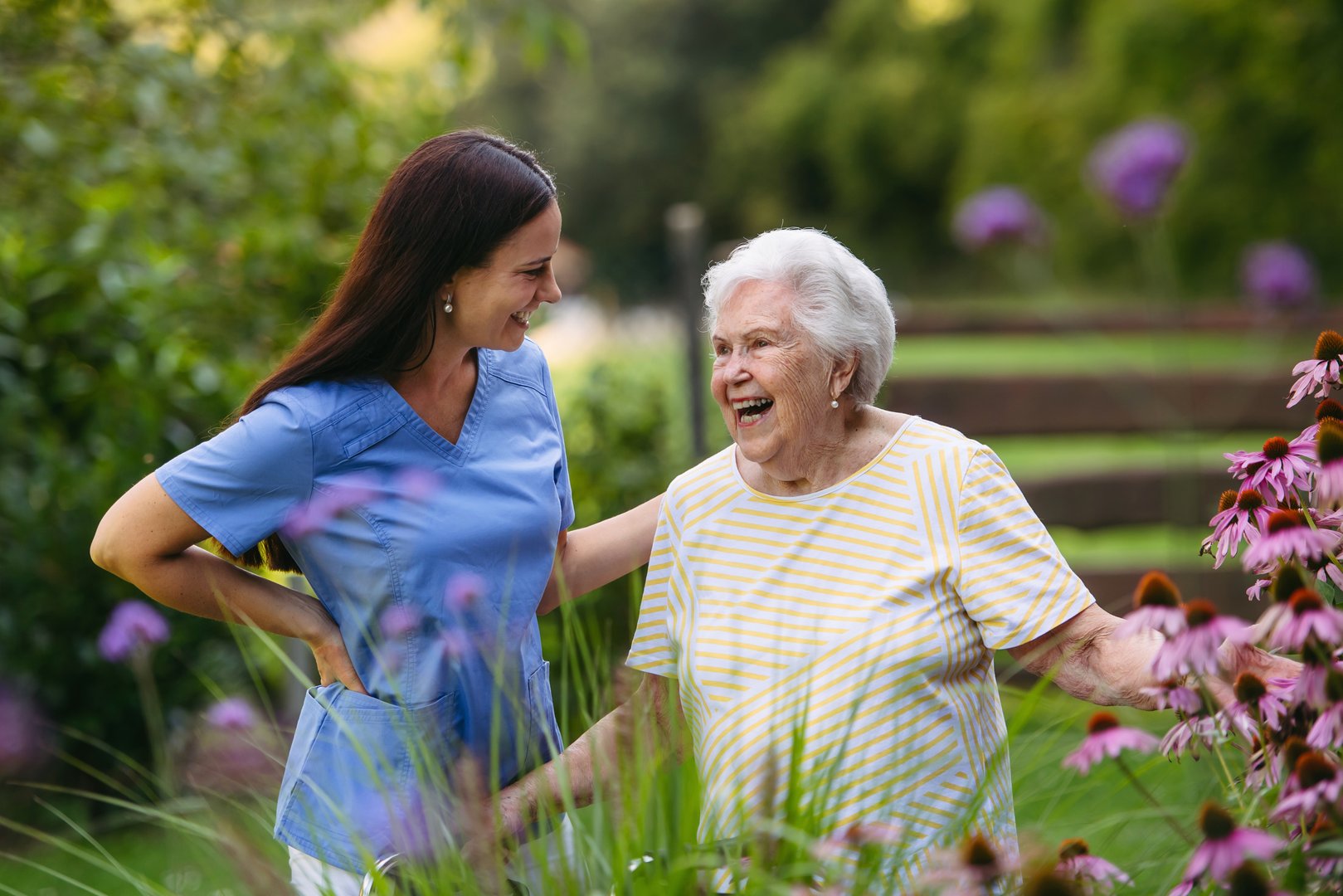 Home care nurse spending time with elderly lady patient in garden.