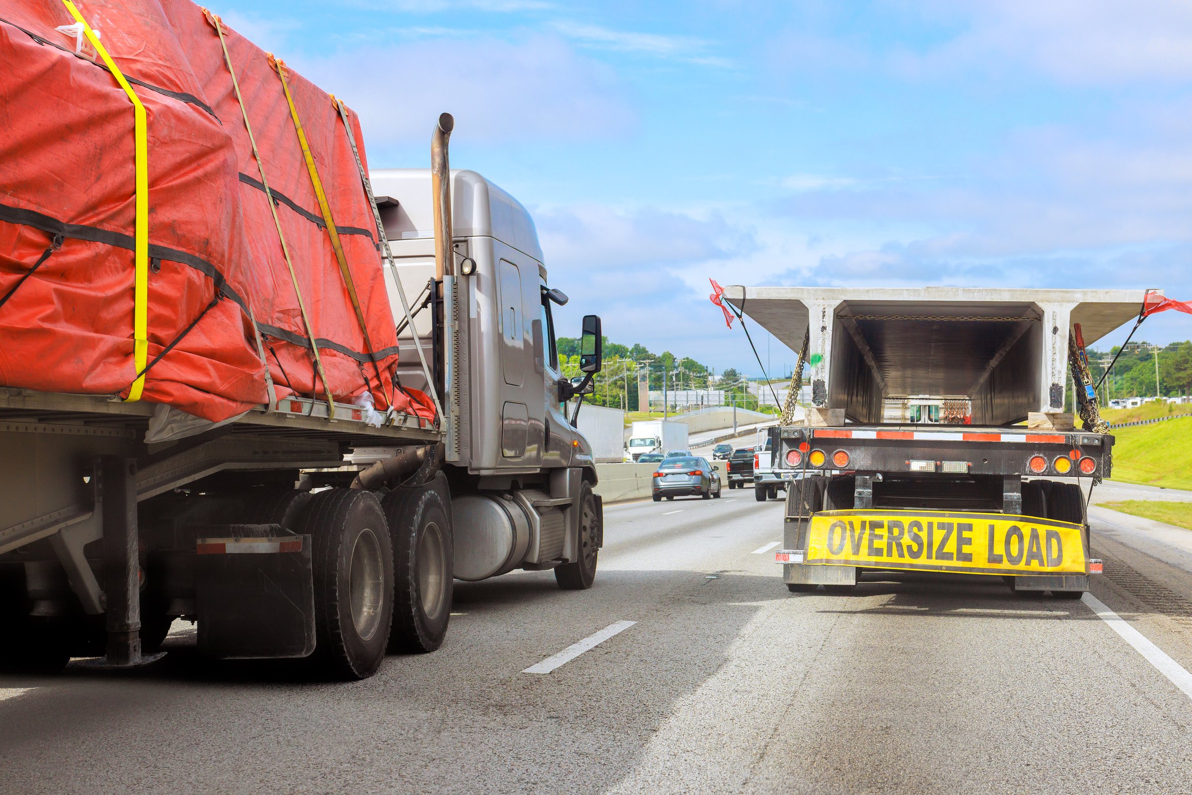 Large trucks carry oversized loads on crowded highway transportation in motion.