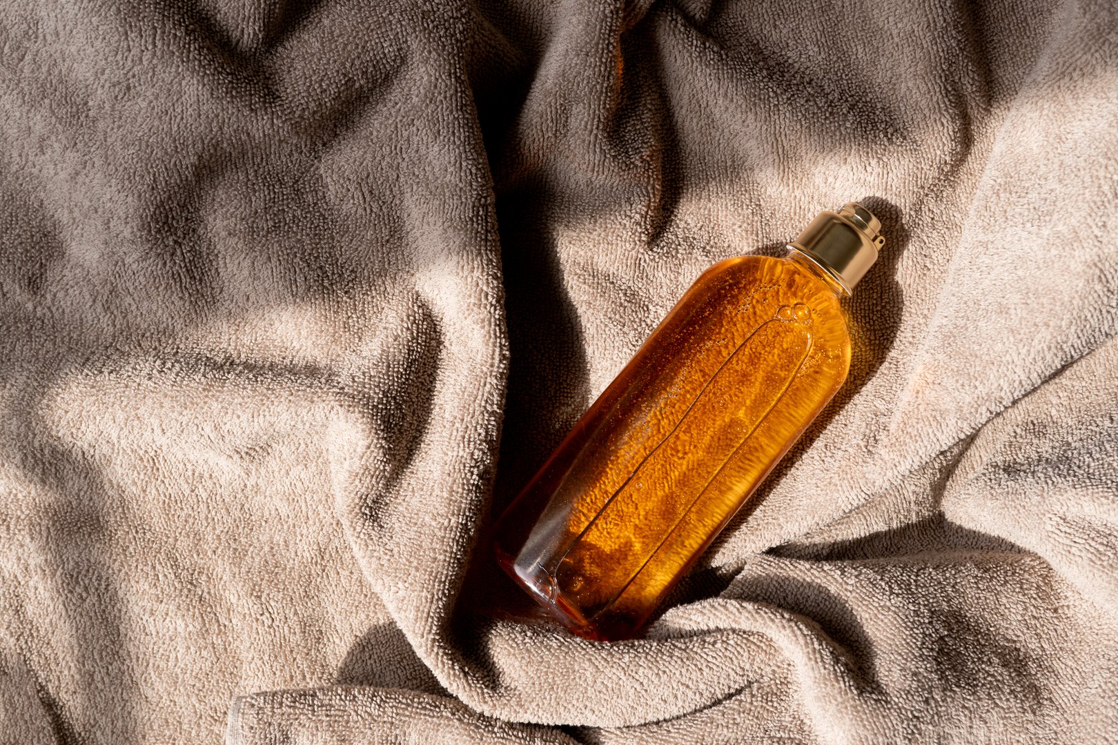 Shower gel, liquid soap or shampoo lies on a cotton towel. Top view with copy space