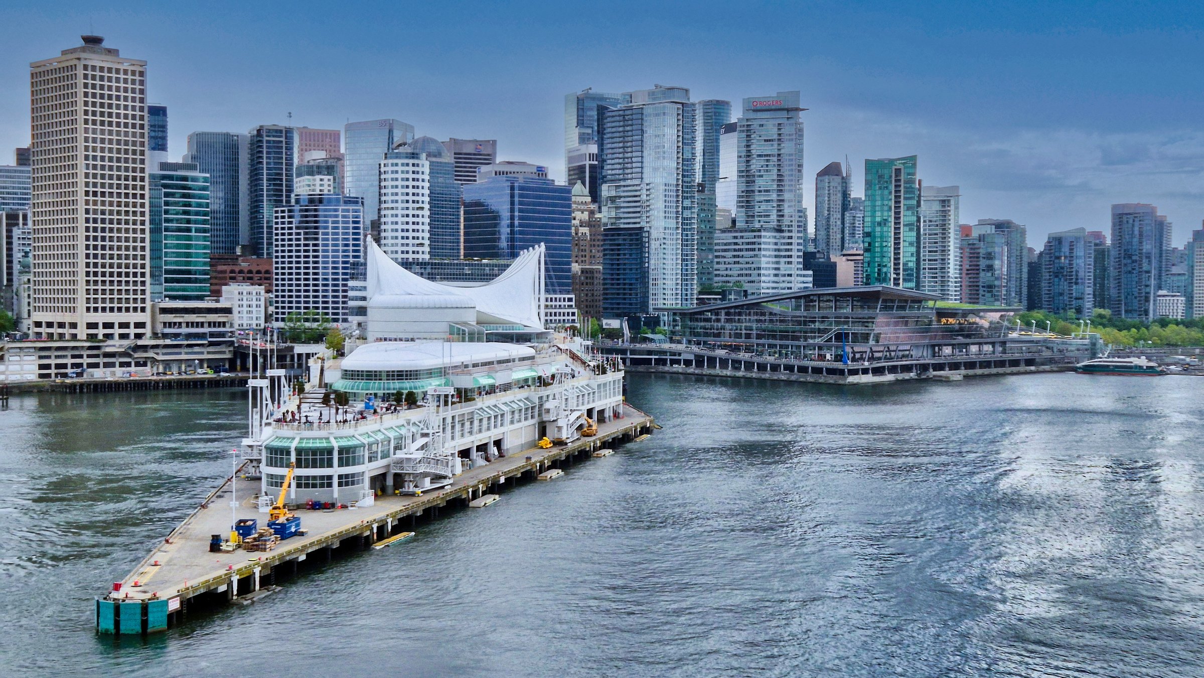 Vancouver, British Columbia, Canada - May 10, 2025 : View of Canada Place, Vancouver's  cruise Terminal, from the sea of Coal Harbor. Built to look like a ship, this iconic complex houses a convention center, world trade center, hotel & ship terminal. On the background are the modern skyscrapers of downtown Vancouver.