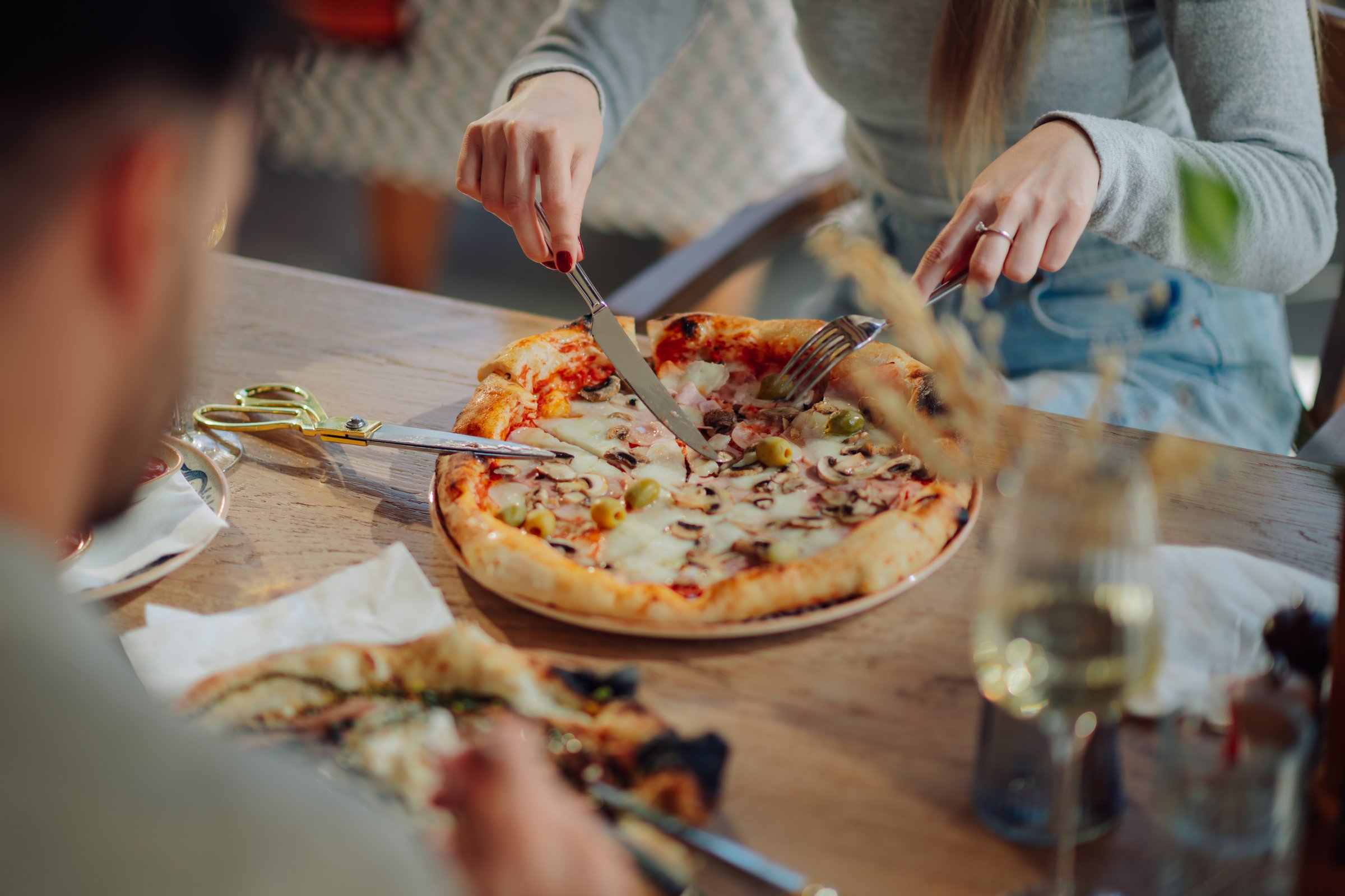 Woman enjoying a delicious pizza in a lively pizzeria, sharing laughter and good times with friends over a delightful meal