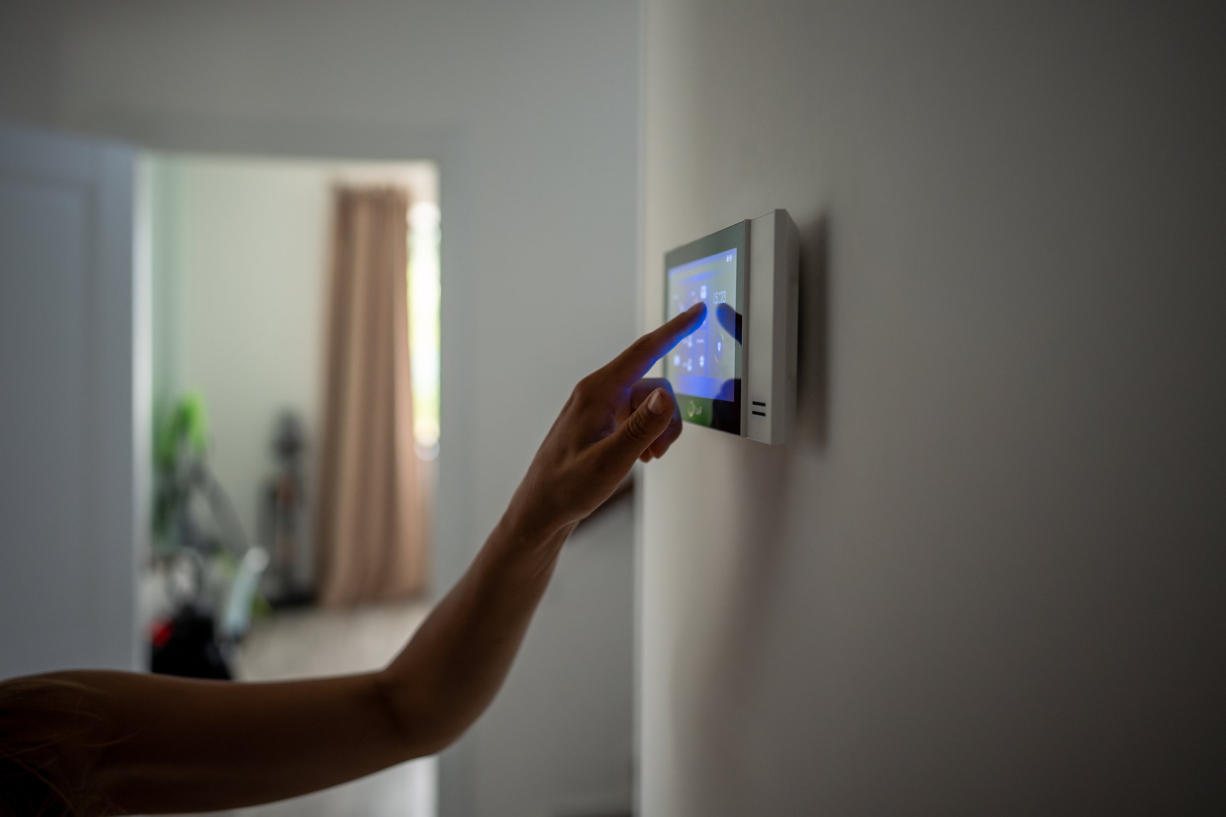 Closeup hand using smart home touch screen with connected appliances device on wall. Setting, checking energy security heating system on digital control in apartment. Home automation monitoring.