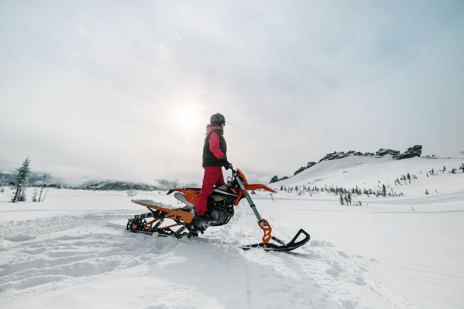Woman rider on winter motorcycle snowbike in mountains landscape during sunny day