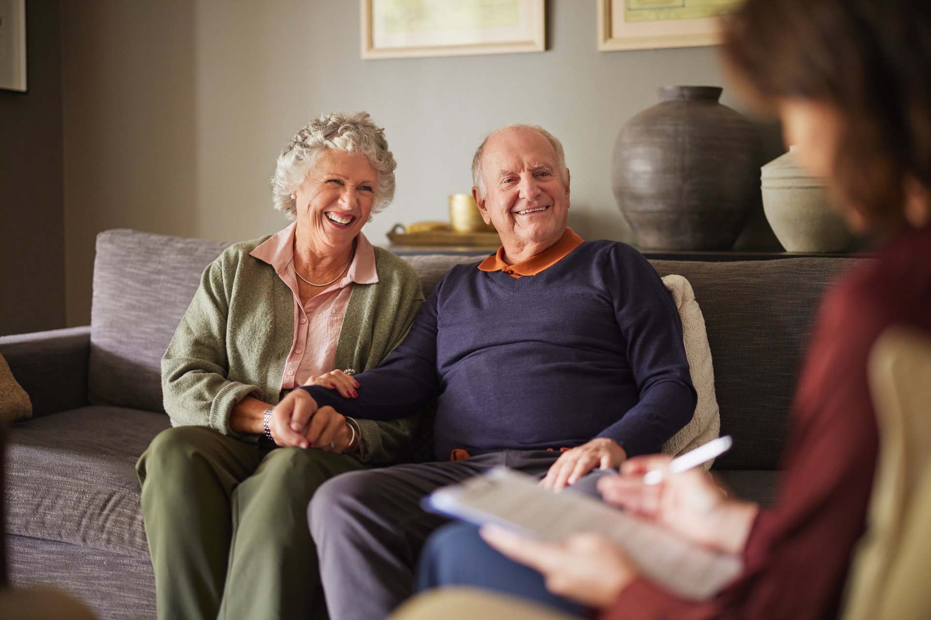 Elderly patients engaging with medical practitioner for health advice and insurance guidance. Senior couple attentively listening to a psychologist woman during consultation at home. Caring female social worker explaining health matters to an elderly couple at home.