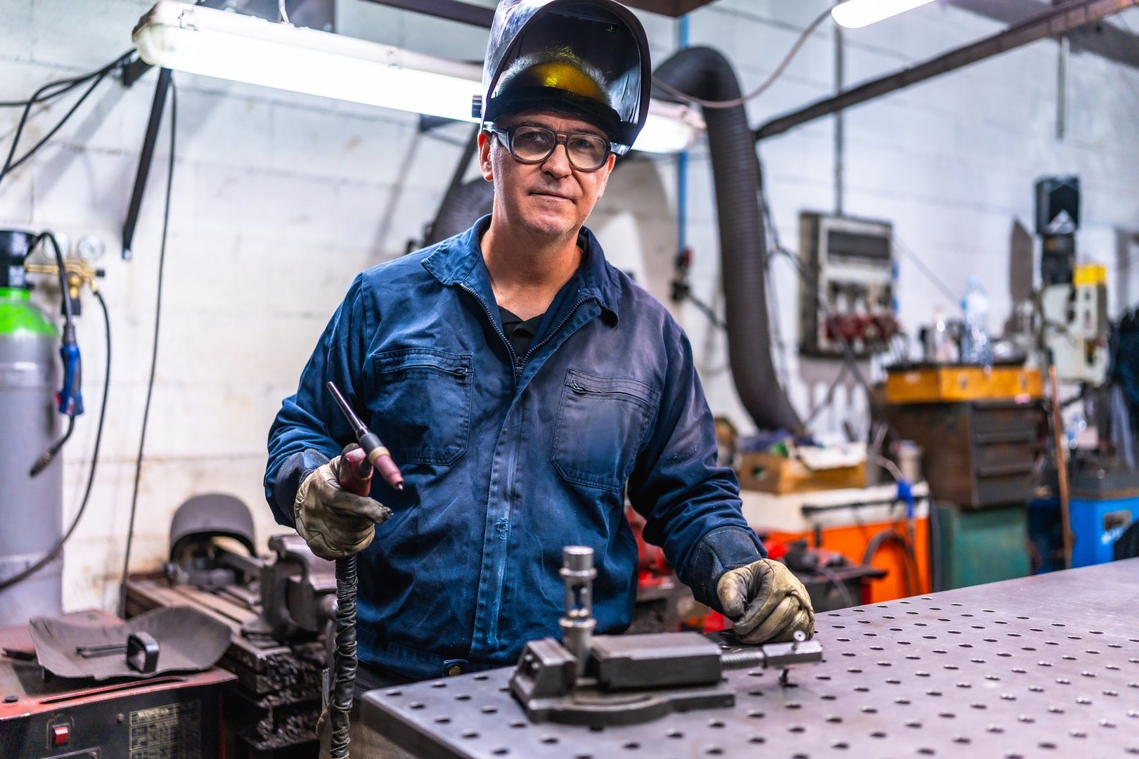 Mature welder standing in a metal factory taking a break and looking at camera