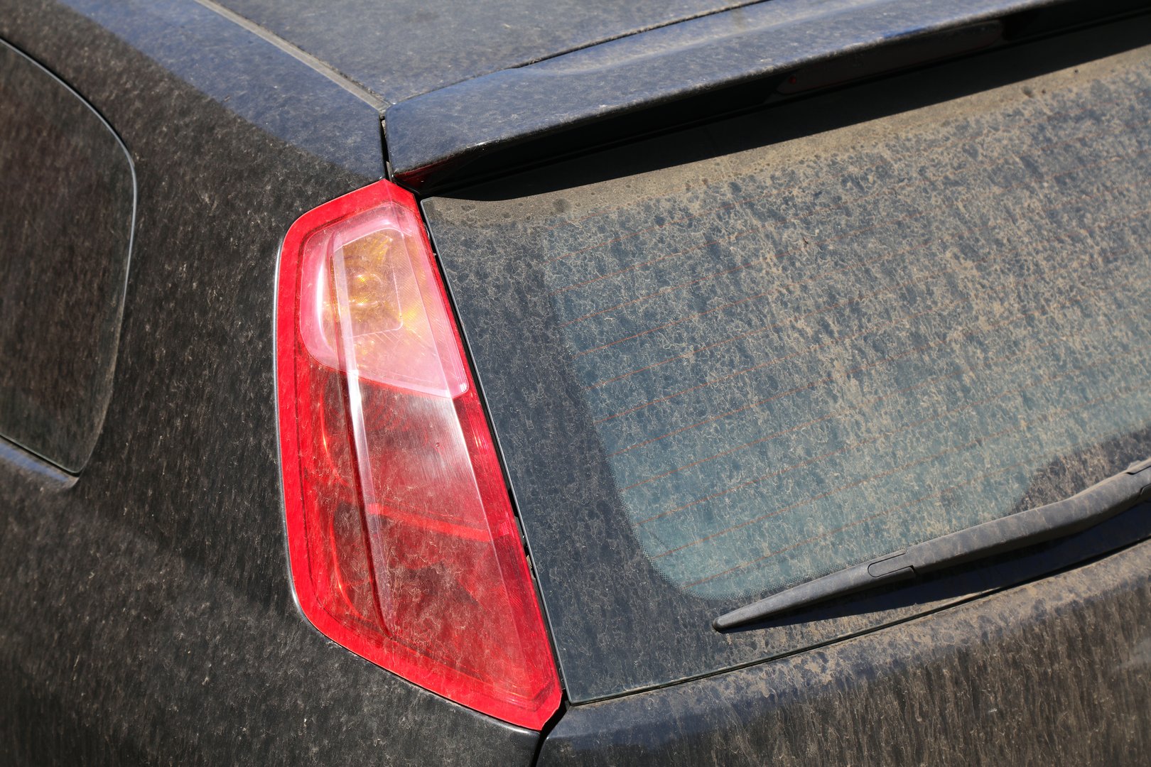Dirty car needs a wash. Small car with dirt on rear windshield.