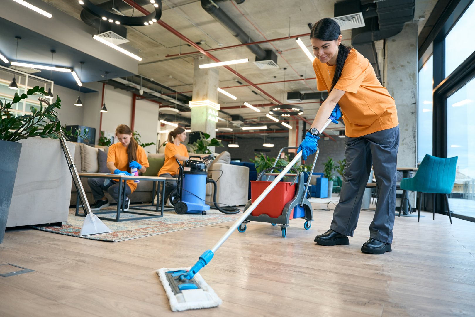 Cleaning company employees are dressed in work clothes, they use a professional vacuum cleaner, a special mop