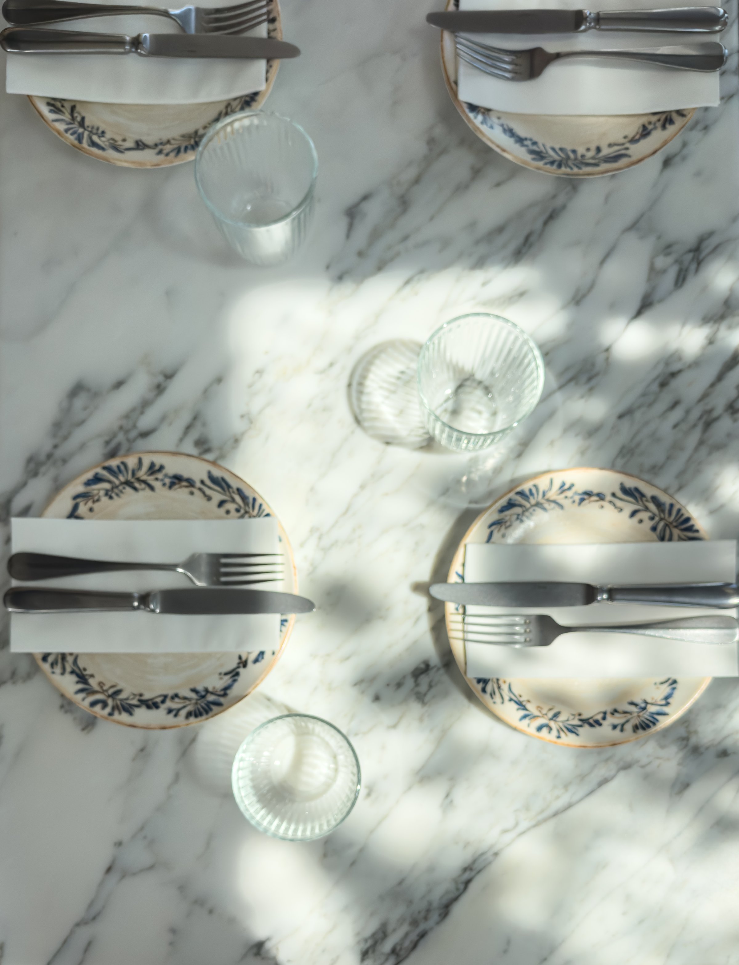 A restaurant table setting captured in natural daylight with light and shadow patterns