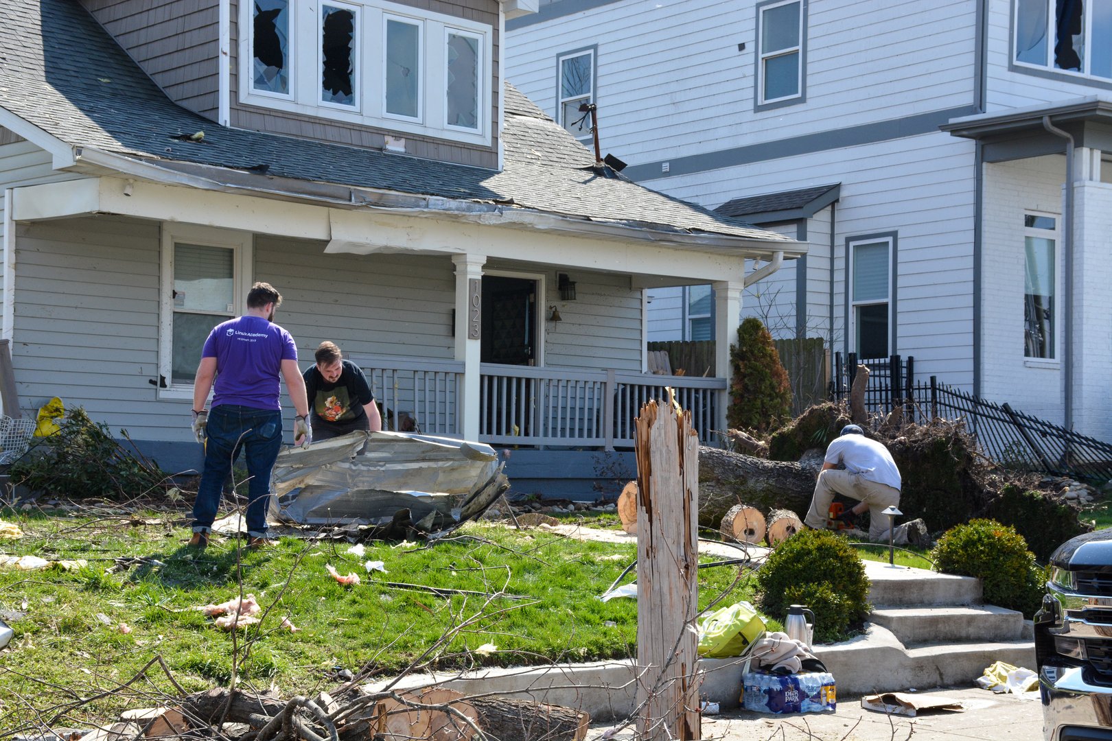 Nashville, Tennessee, 2020: People clean trash from their yard and start to cut a fallen tree the morning after a tornado rips through Nashville, Tennessee.
