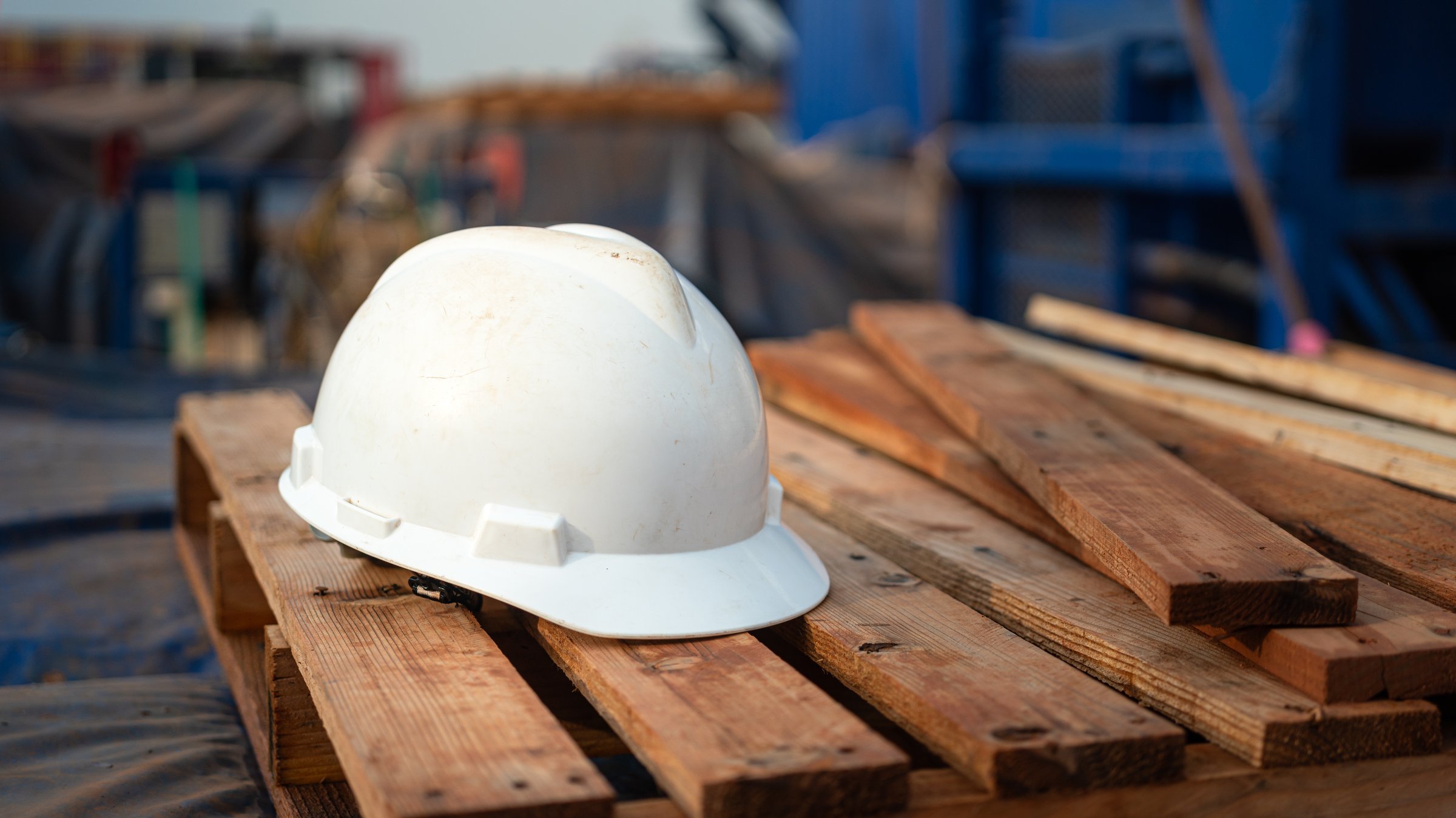 A white safety helmet or protective hardhat is placed at the construction site. Industrial safety PPE object, ready to working at unsafe workplace concept. Close-up.