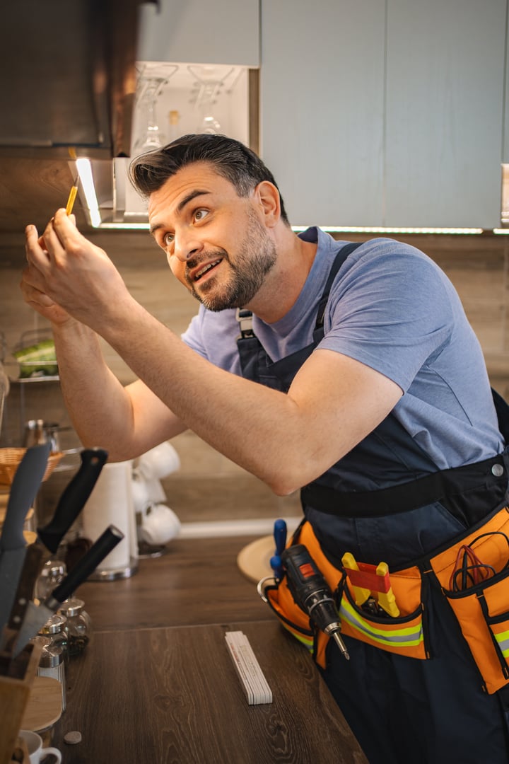 Electrician working on led lights installation under kitchen cabinets