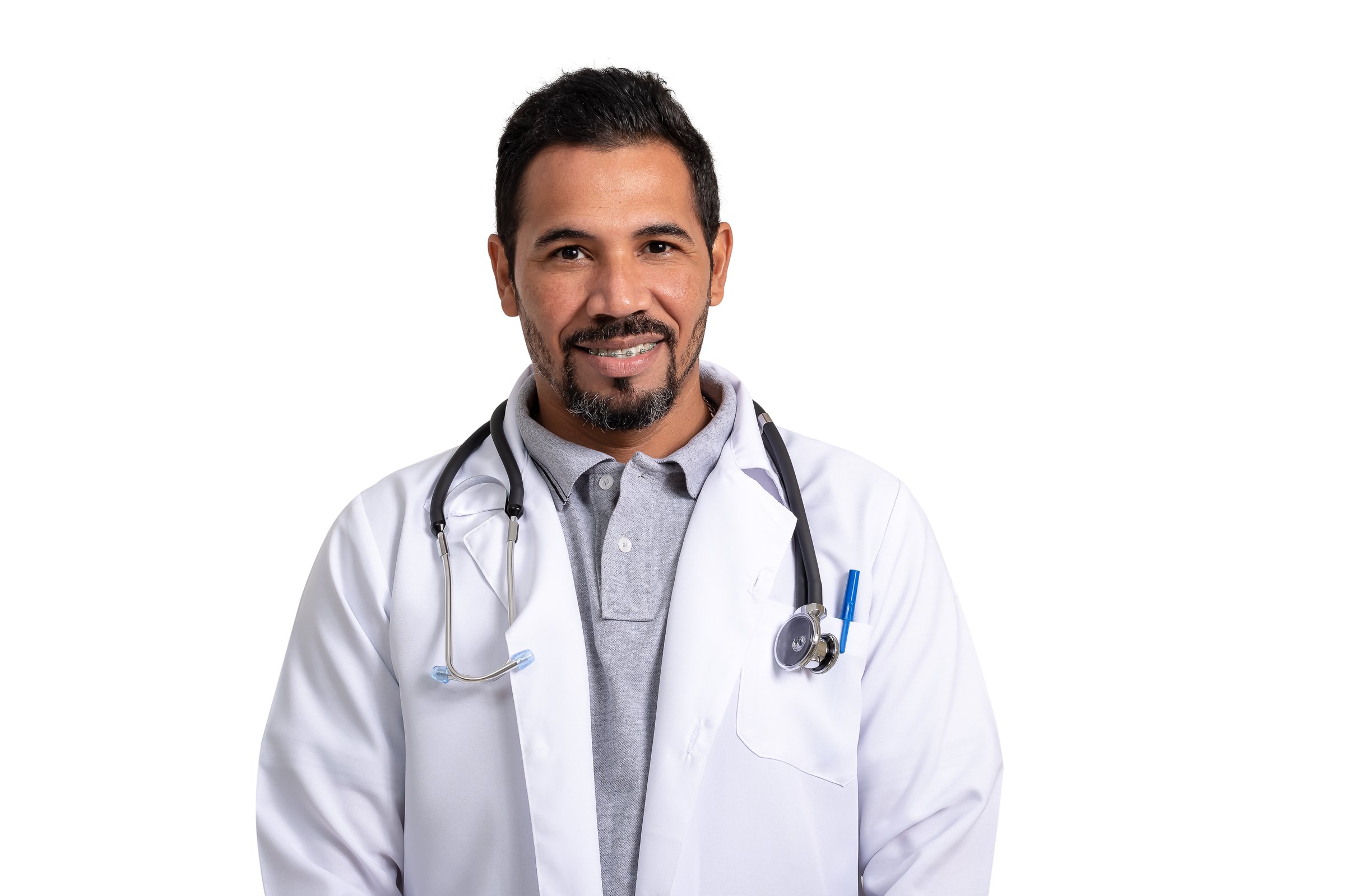 Doctor, man wearing uniform and with a stethoscope looks at camera and smiles, isolated on white background