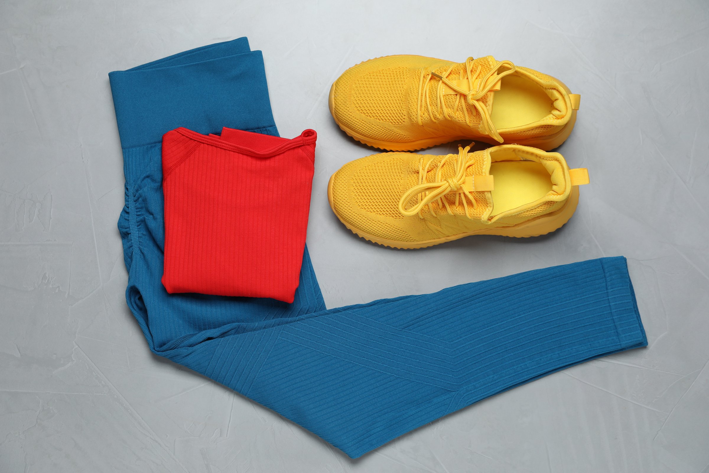 Sportswear and shoes on grey background, flat lay