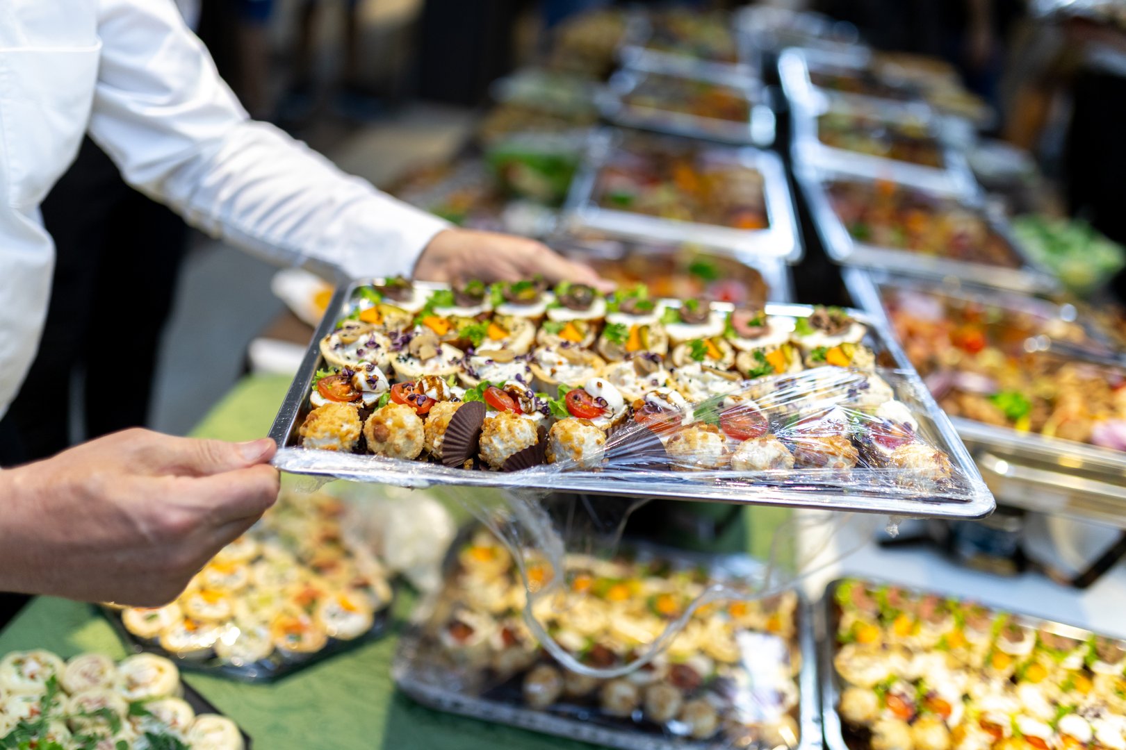 A server holds a tray filled with a variety of beautifully arranged appetizers at a sophisticated event, showcasing culinary delights for guests.