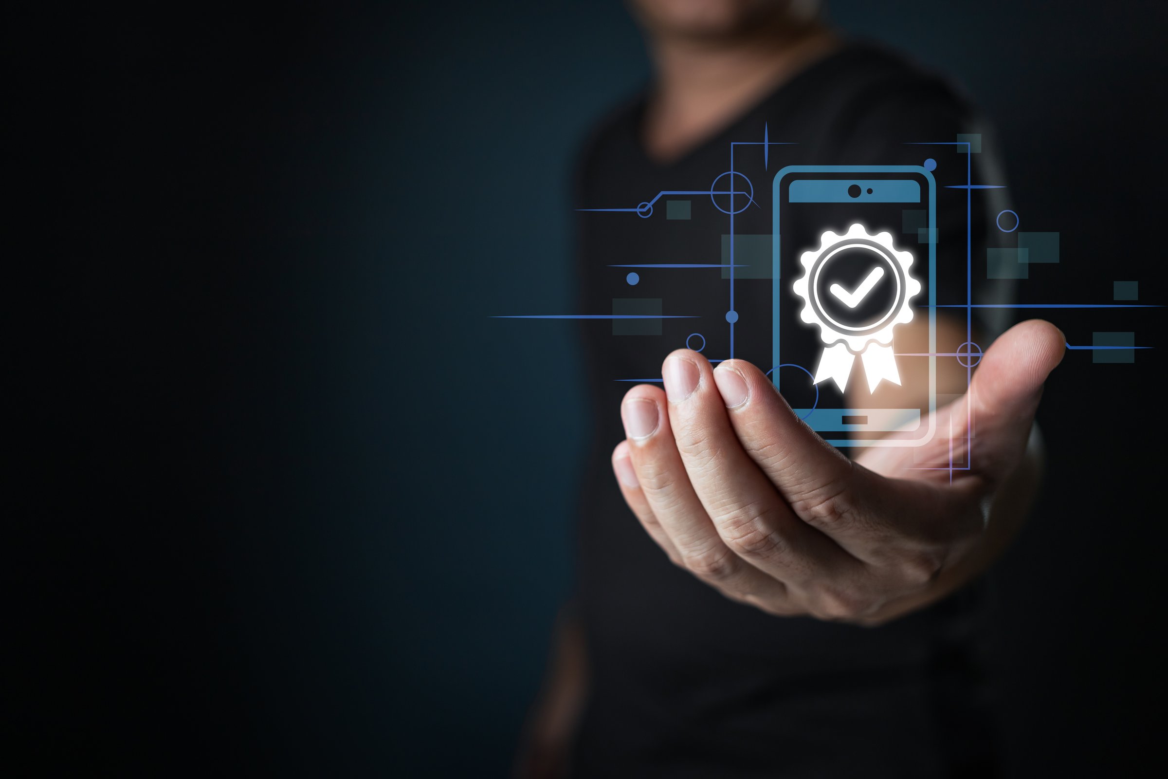 Quality assured. A man hand holding smartphone displaying a certified checkmark. Emphasizing trust, reliability, and high standards.