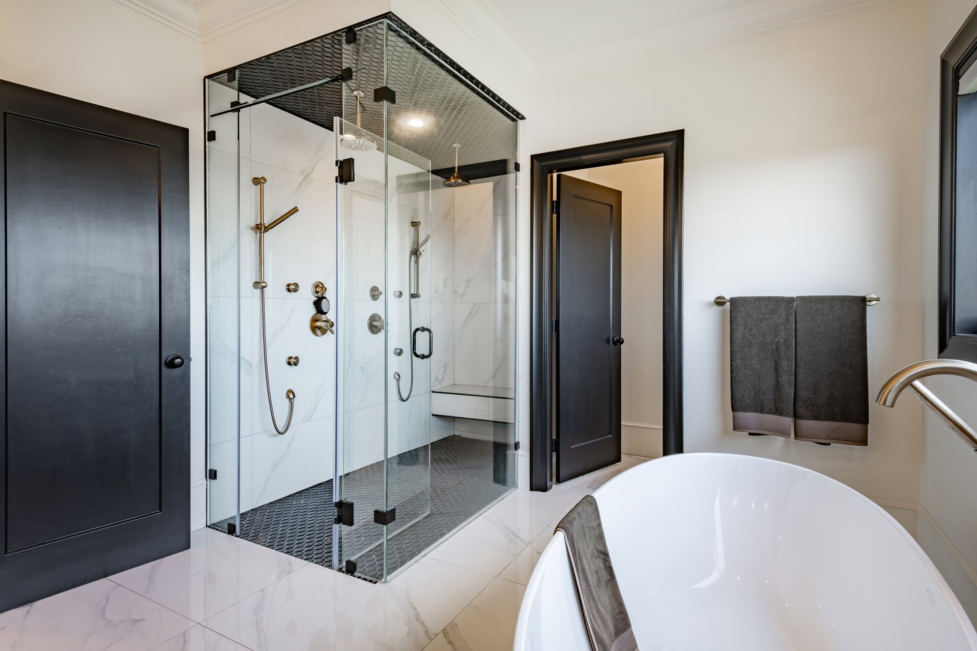 Very large bathroom with luxury decor glass wall shower free standing bathtub double sinks subway tile sauna black cabinets tiled walls built in shelving