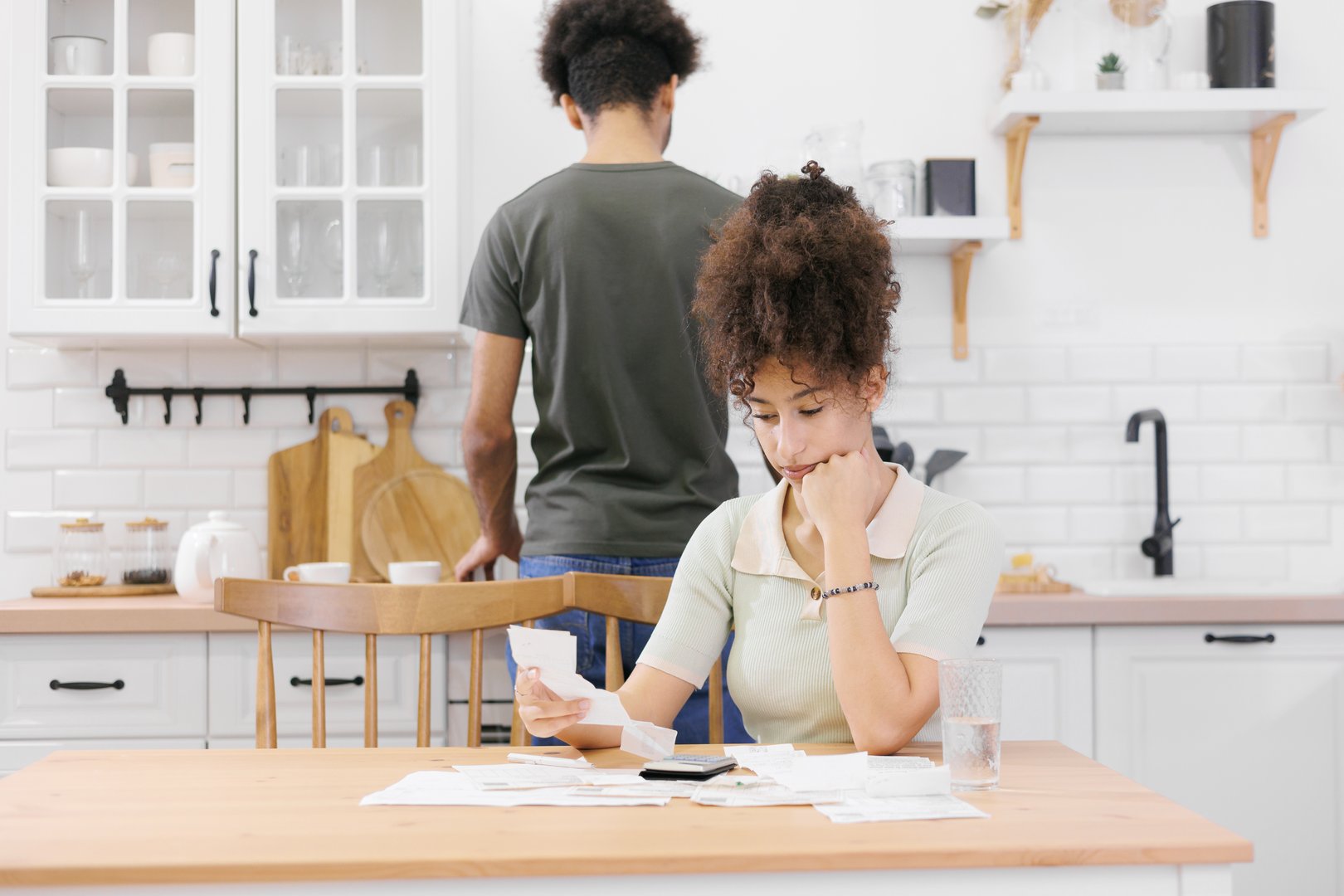woman pays electricity rent bills, man cooks lunch. African American young married person kitchen count expenses calculator. support care, payment utilities taxes, financial obligations mortgage loan