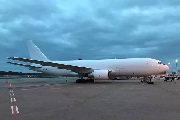 Large white cargo airplane parked on a runway under a cloudy sky, with no visible branding or markings.