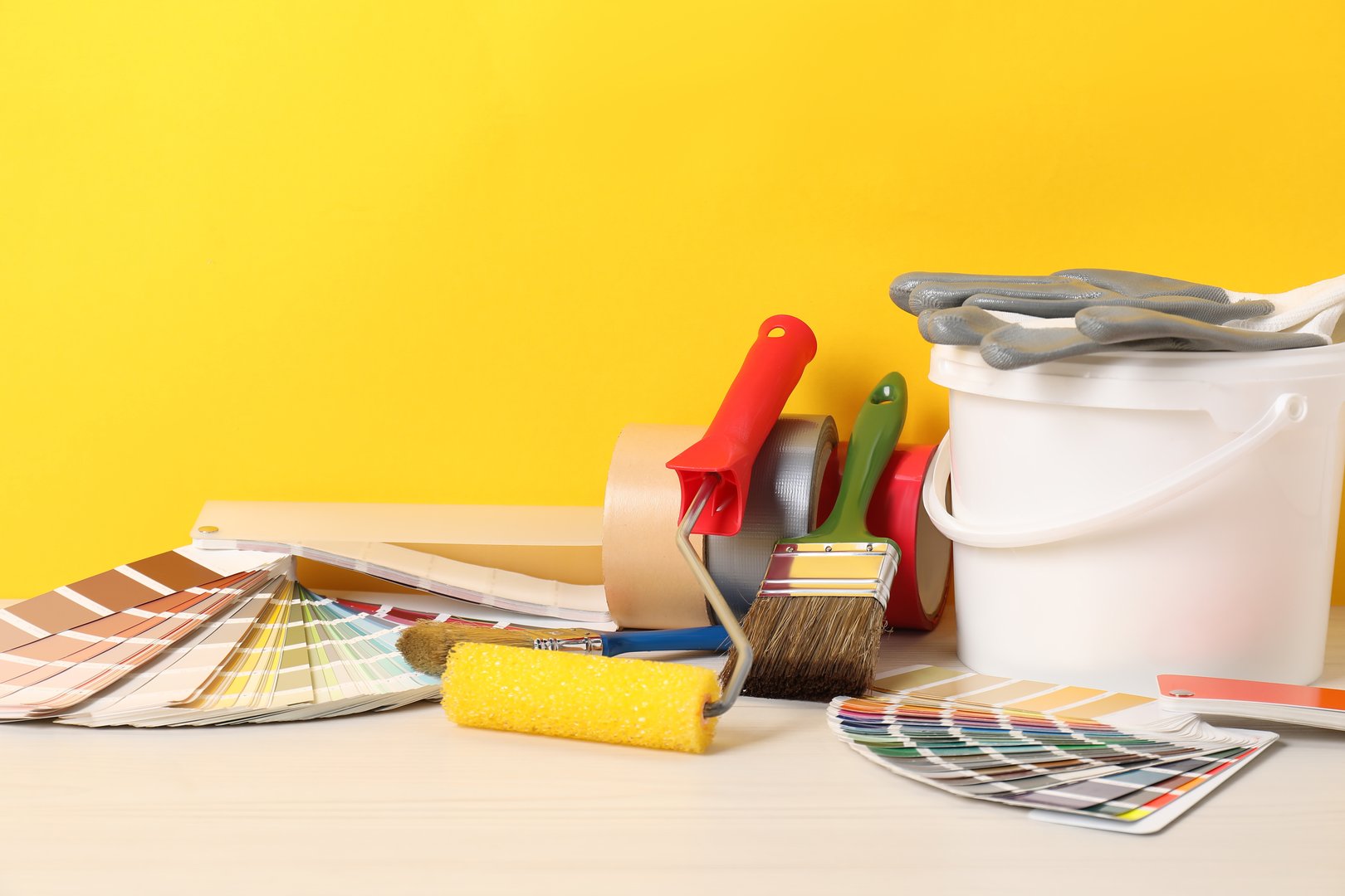 Different painter's tools on white wooden table. Decorating and design