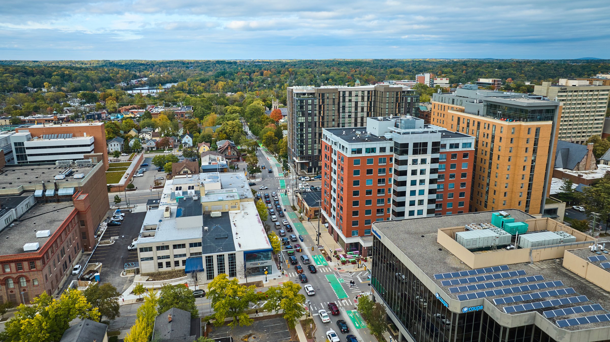 Aerial view of Downtown Ann Arbor, Michigan, showcasing architectural diversity, autumn hues, and eco-friendly solar panels.