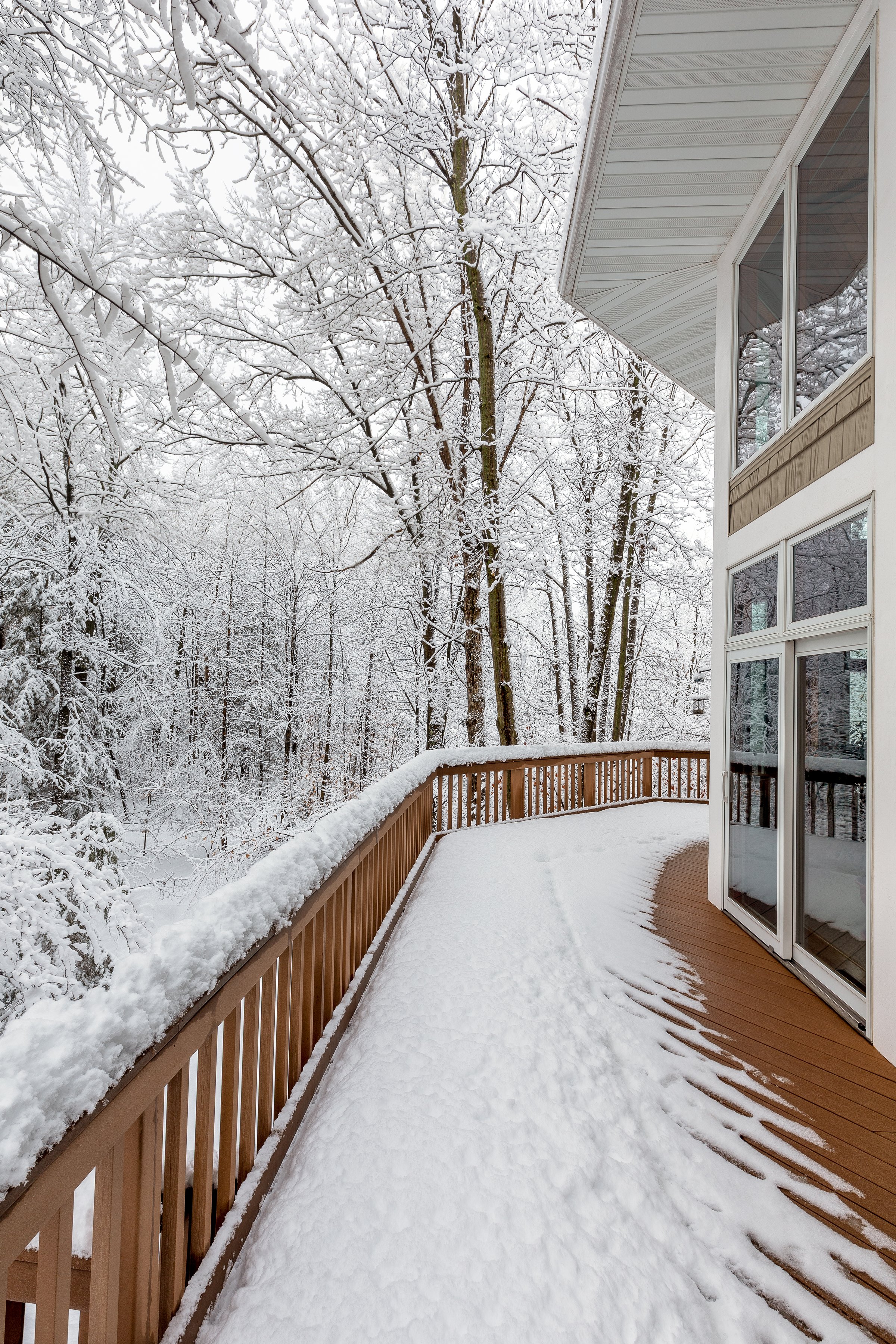 Large composite deck on a luxury home in the woods in snow in winter.  Concepts could include architecture, design, outdoor living, luxury living, nature, seasons, other.
