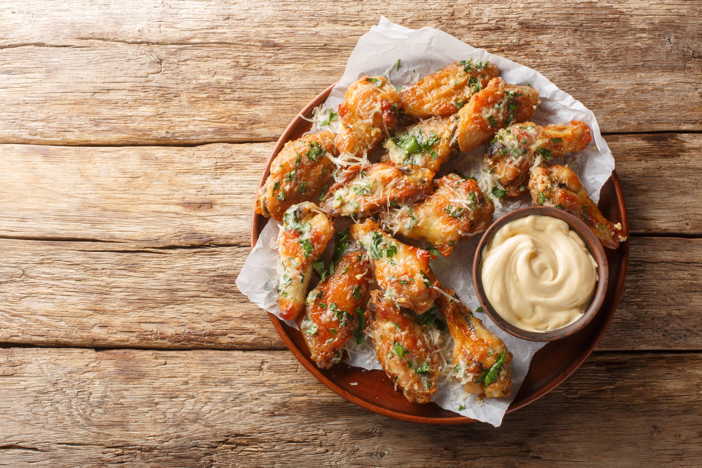Classic Garlic Parmesan Butter Chicken Wings served with mayonnaise close-up in a plate on the table. Horizontal top view from above