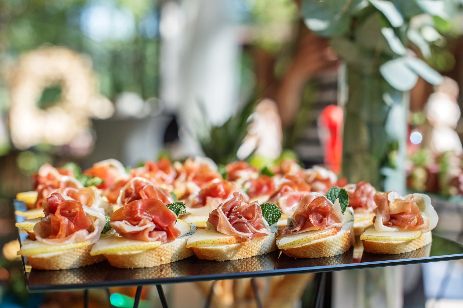 catering buffet table with snacks and appetizers. Set of canapés with jamon, bruschetta, pear and cheese and mint