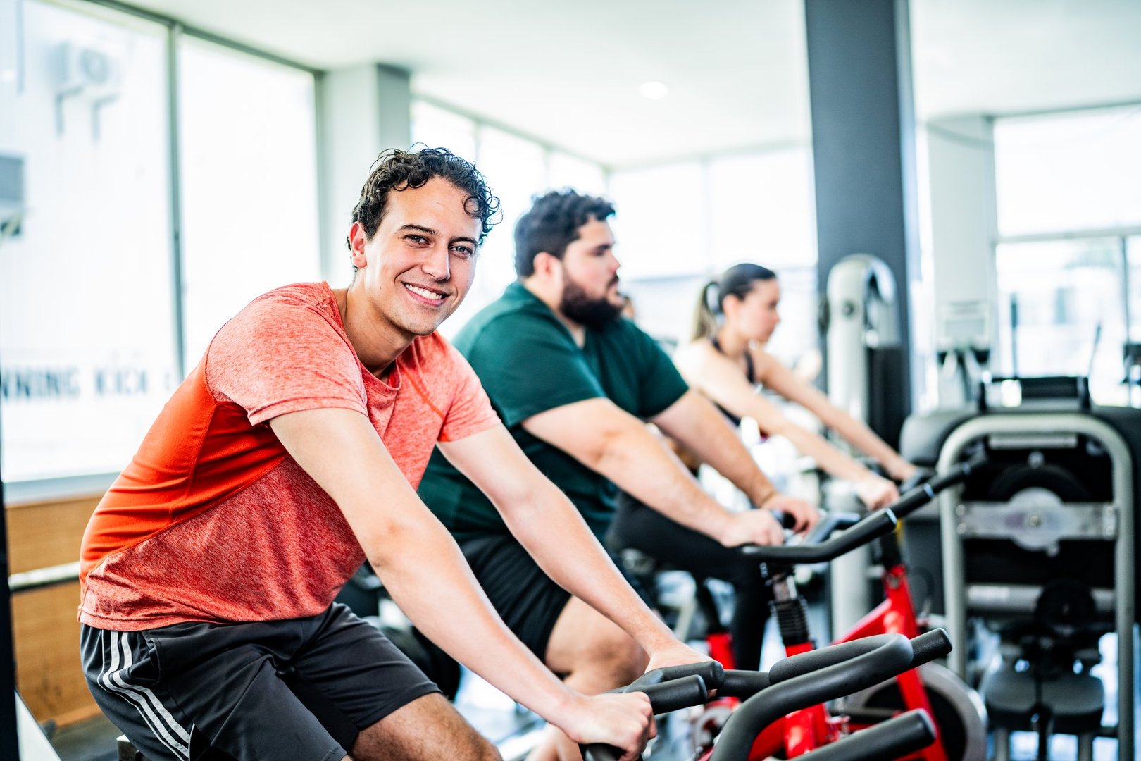 Portrait of young man on exercise bike at gym