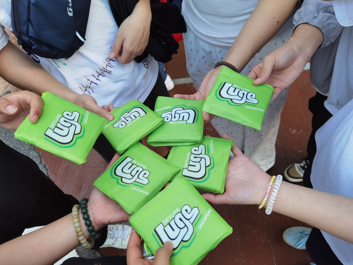 Several people holding green luge-branded pouches in their hands, each pouch featuring a white luge logo.