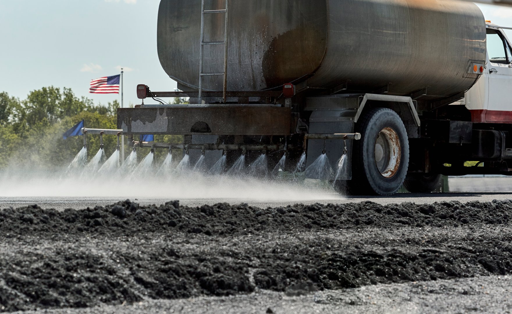 Water truck spraying water on roadway in preparation for construction