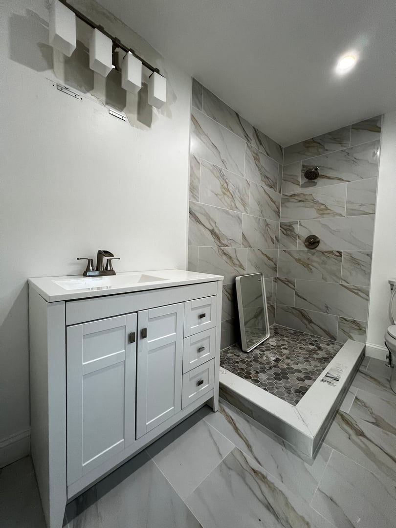 3d render - a modern bathroom with green wall tile and terrazzo wall and floor tile, brass plumbing fixtures , brass mirrors and marble countertop	. An eclectic luxurious design