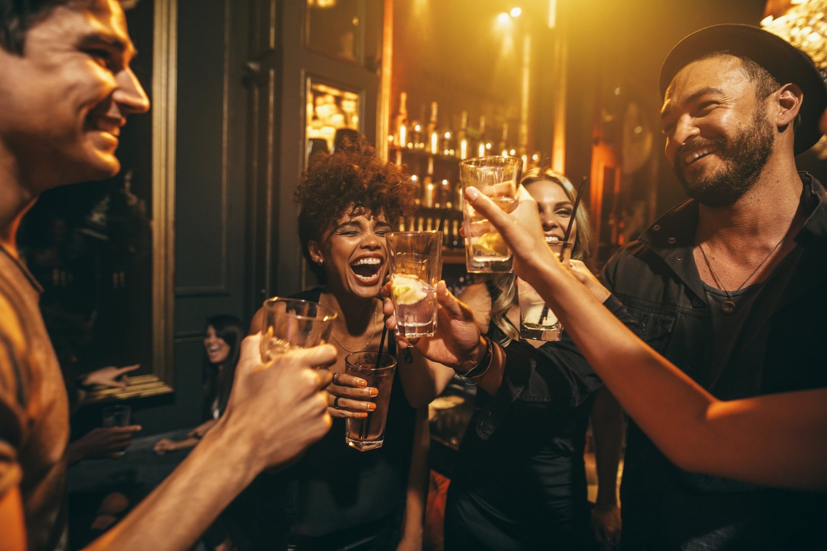 Shot of young men and women enjoying a party. Group of friends having drinks at nightclub.