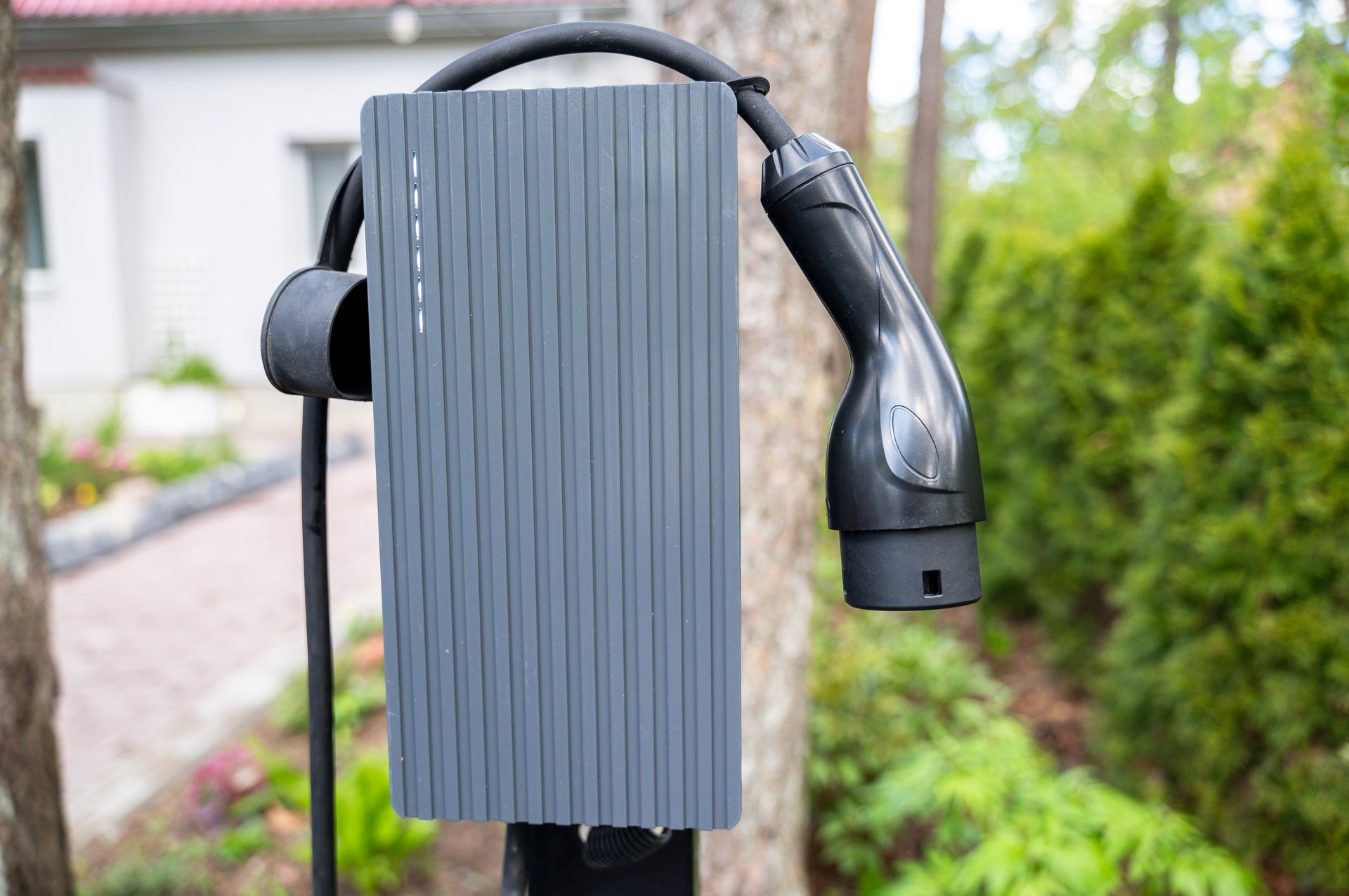 Close-up view of electric vehicle charger mounted outdoors in home driveway