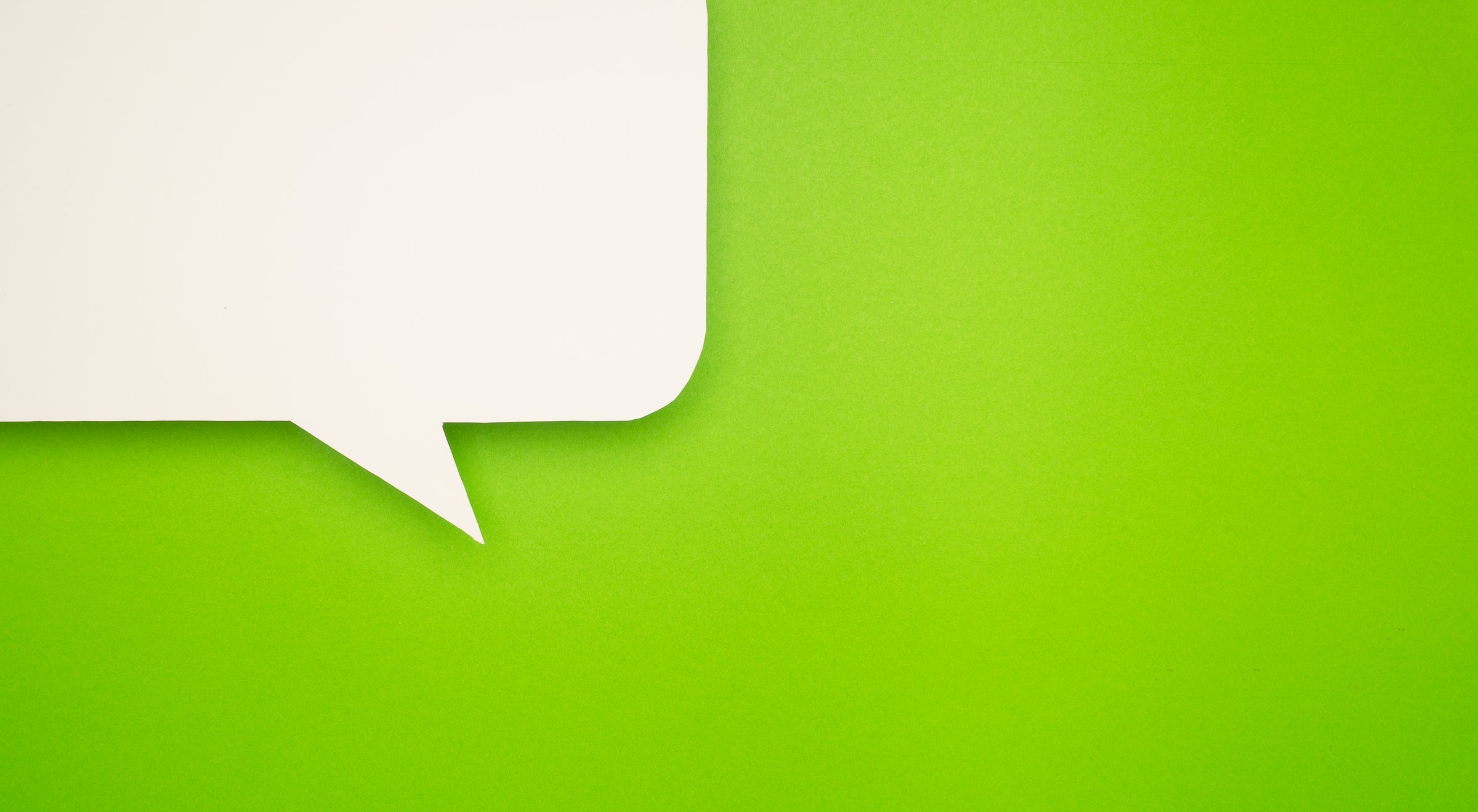 Close-up of a blank white speech bubble on a bright green background, representing communication, conversation, social media, and messaging concepts in a modern, minimalist style.