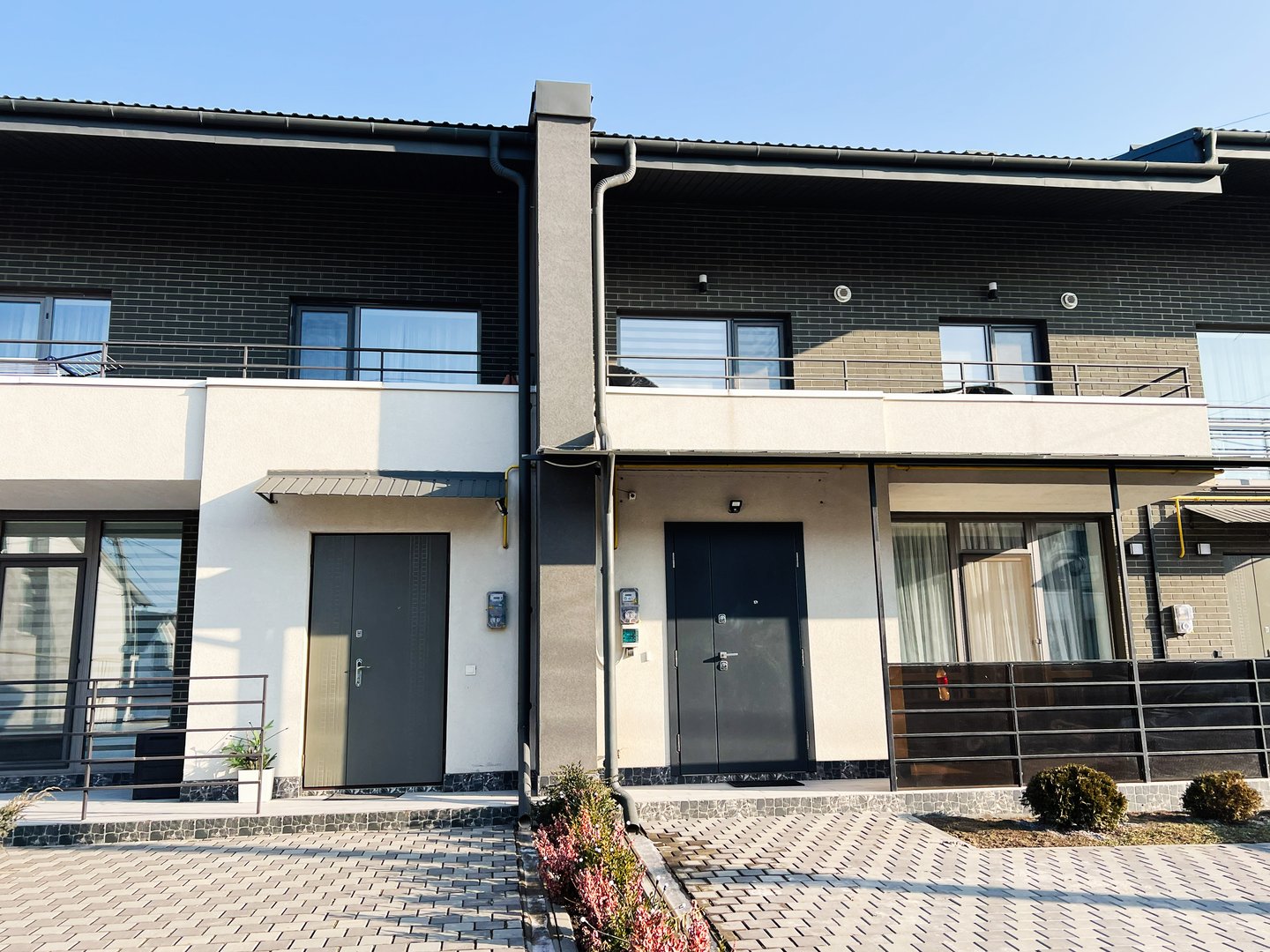 Klenovi Hai, Ukraine - February 27, 2025: Exterior view of a modern duplex building with paved walkway and landscaping